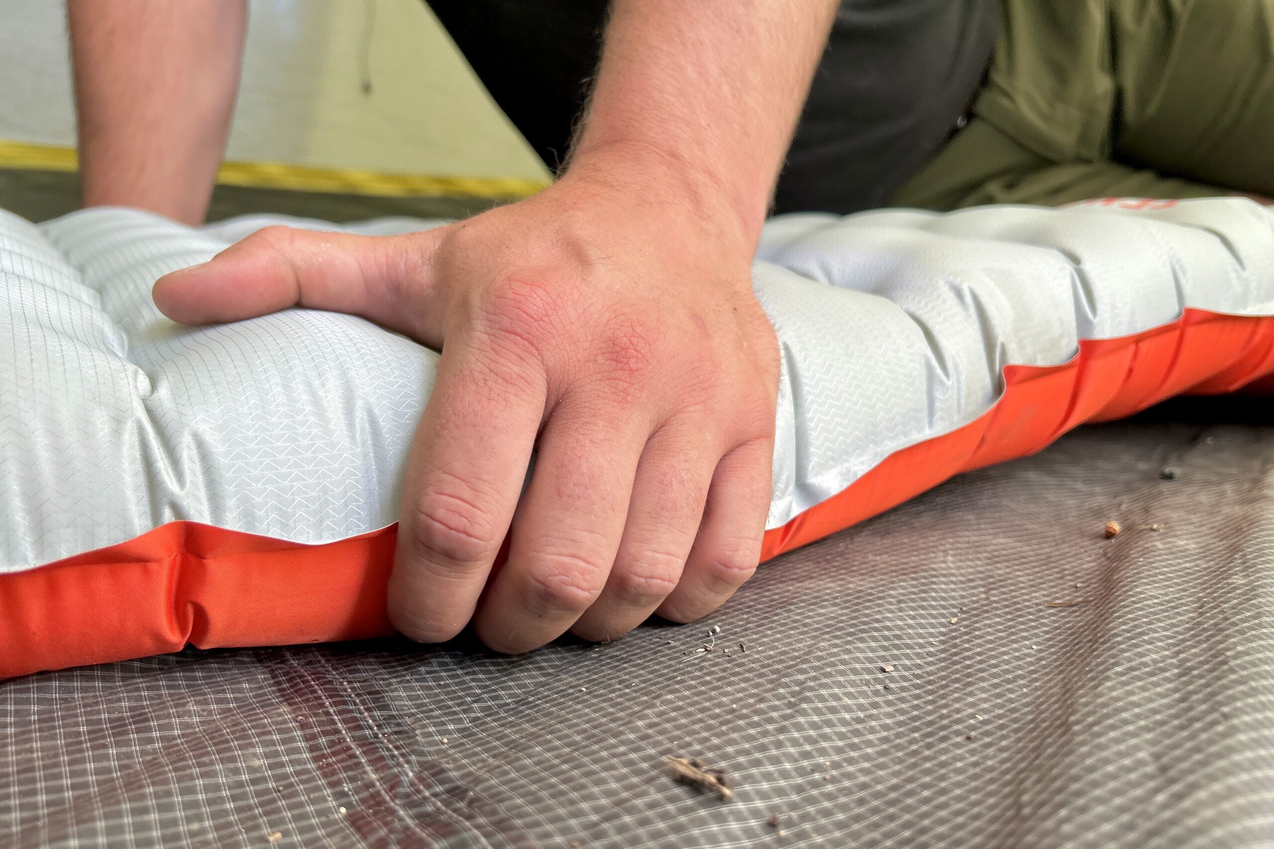 A person grips the side of a sleeping pad.