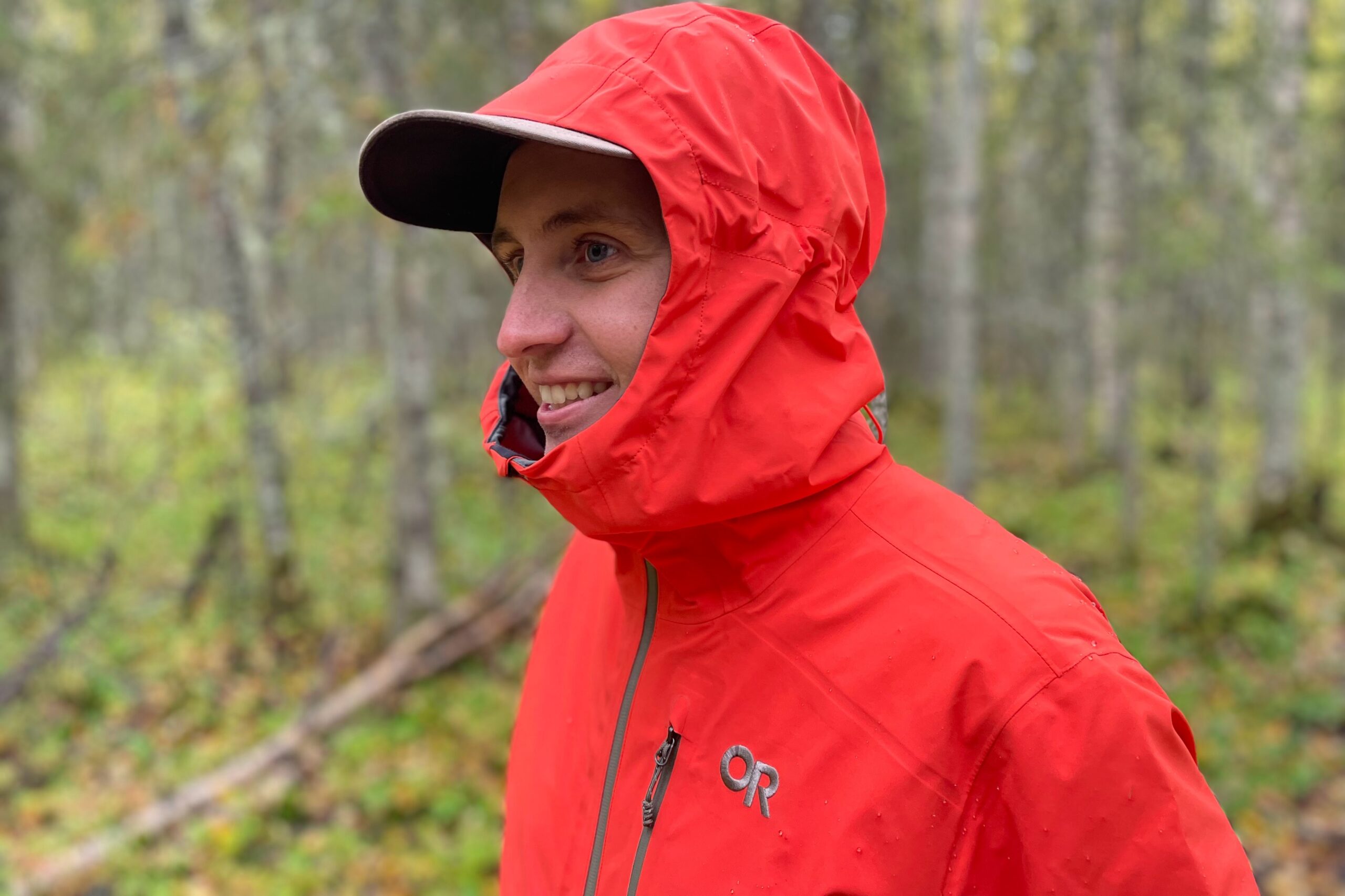 A man stands in a forest with his hood up.