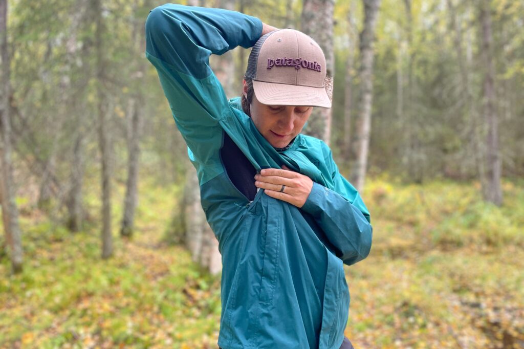 A man unzips the vents of his rain jacket.