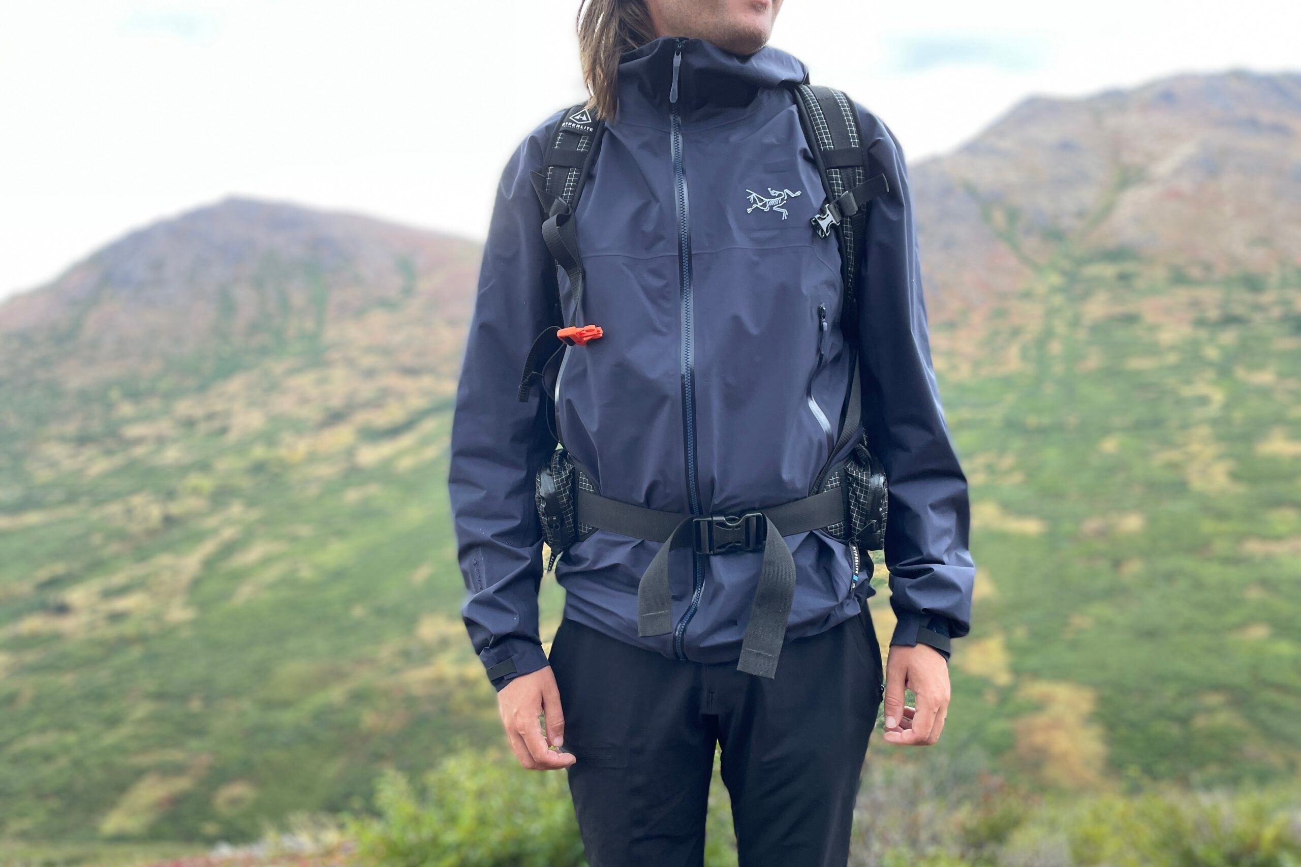 A closeup of the front of a rain jacket with mountains in the background.