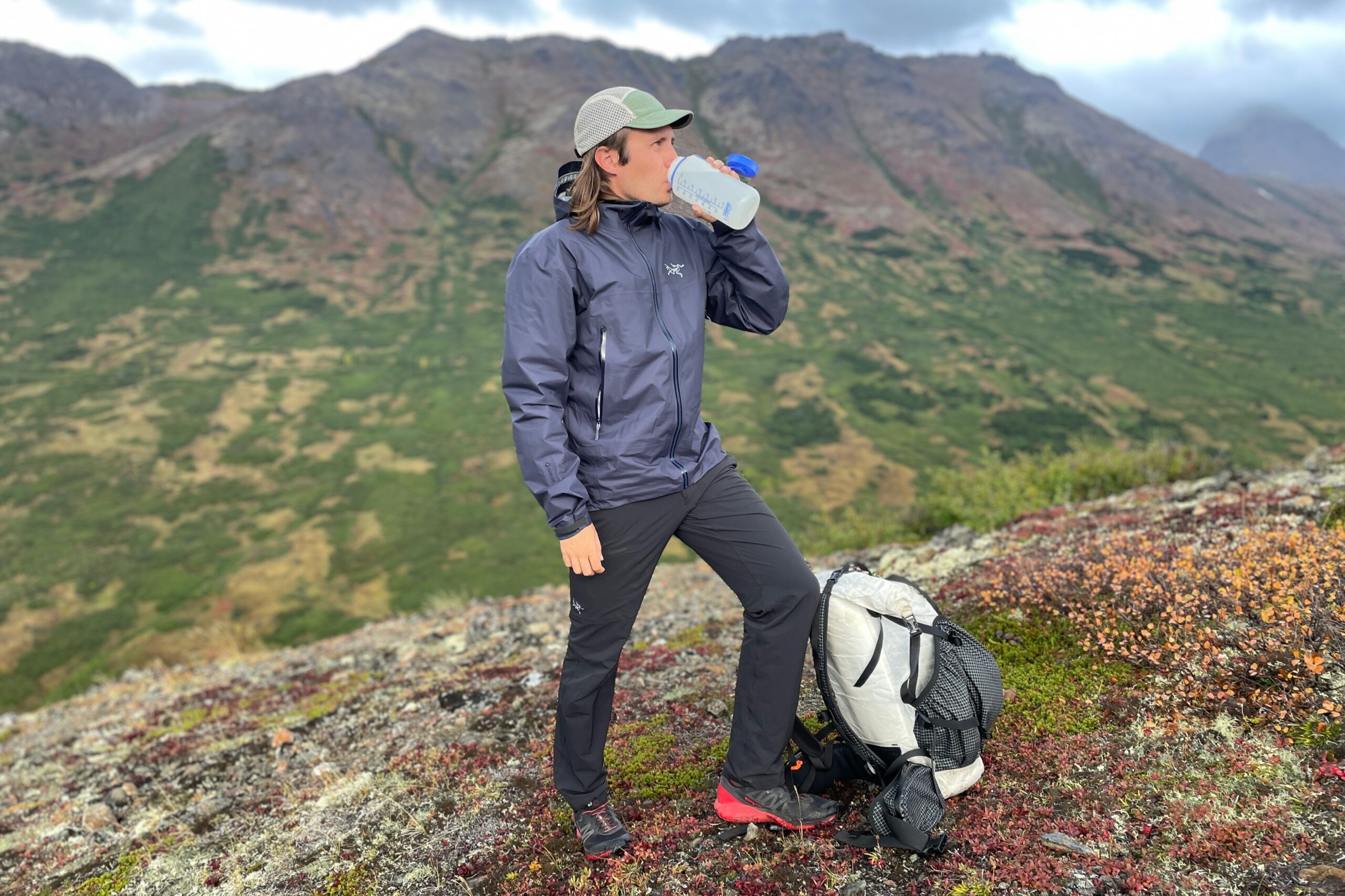 A man drinks from his water bottle on an alpine hike.