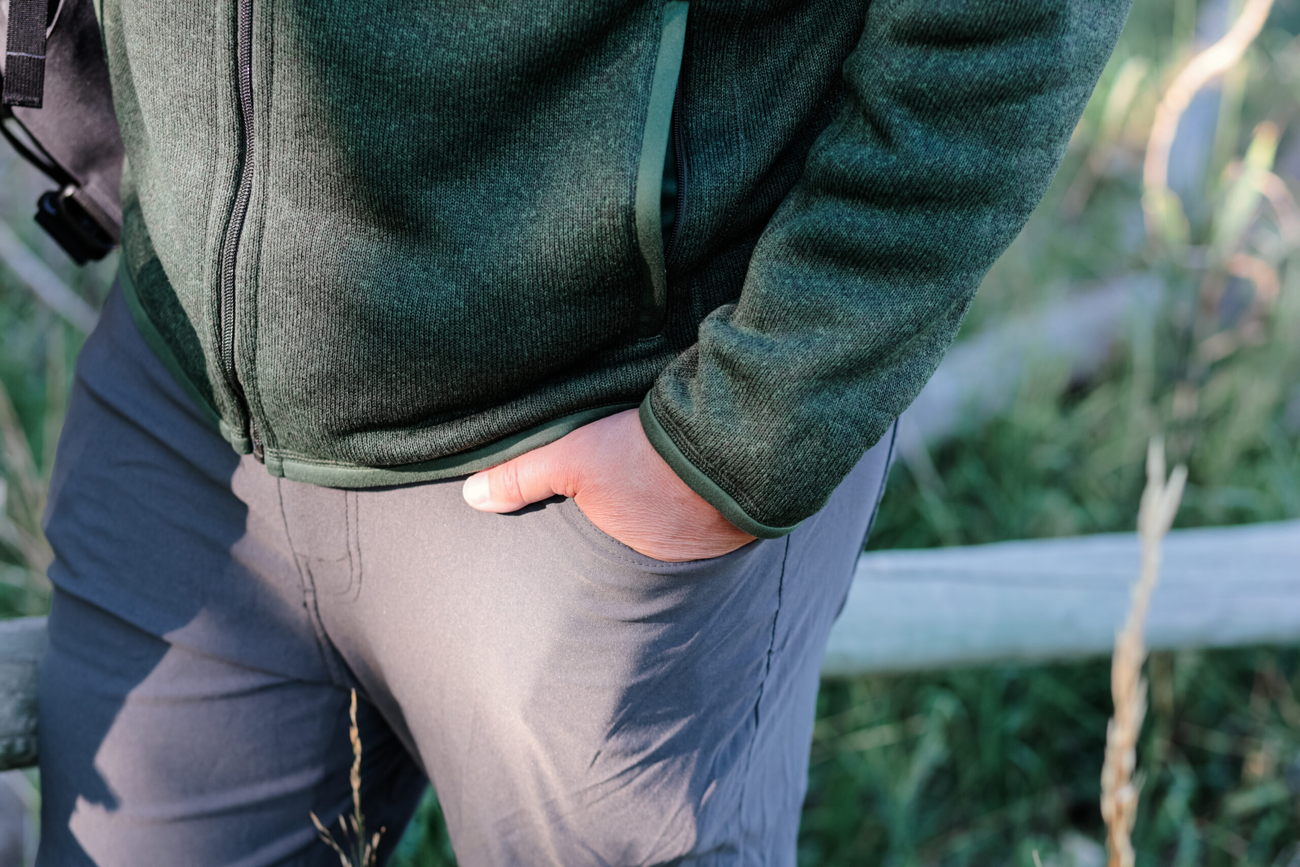 A man's hand in his hip pocket wearing a green fleece.