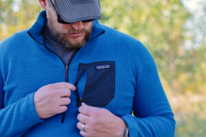 A hand unzips a chest pocket on a fleece.