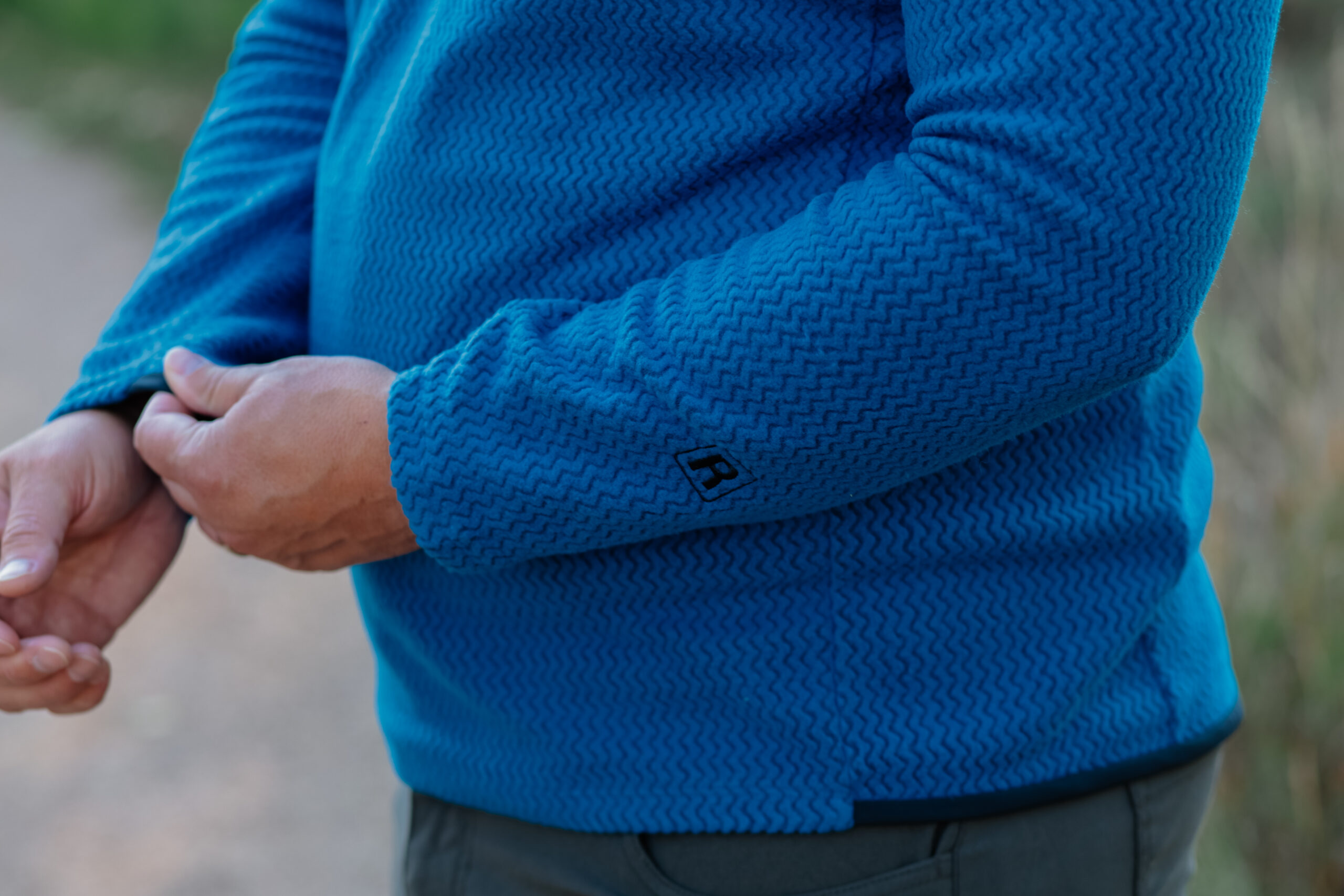 A hand adjusts the cuff of a fleece.