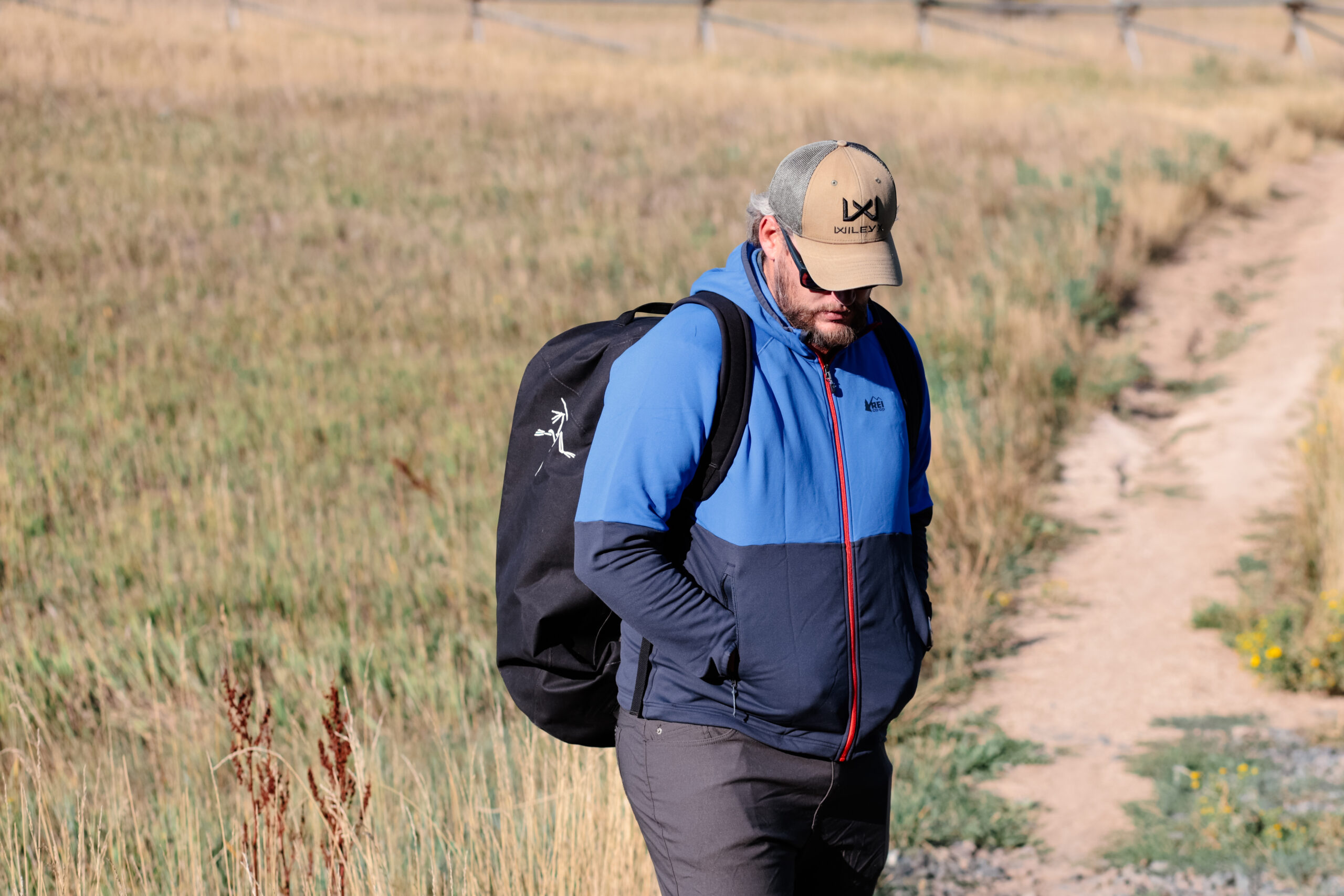 A man carries a backpack down a trail.