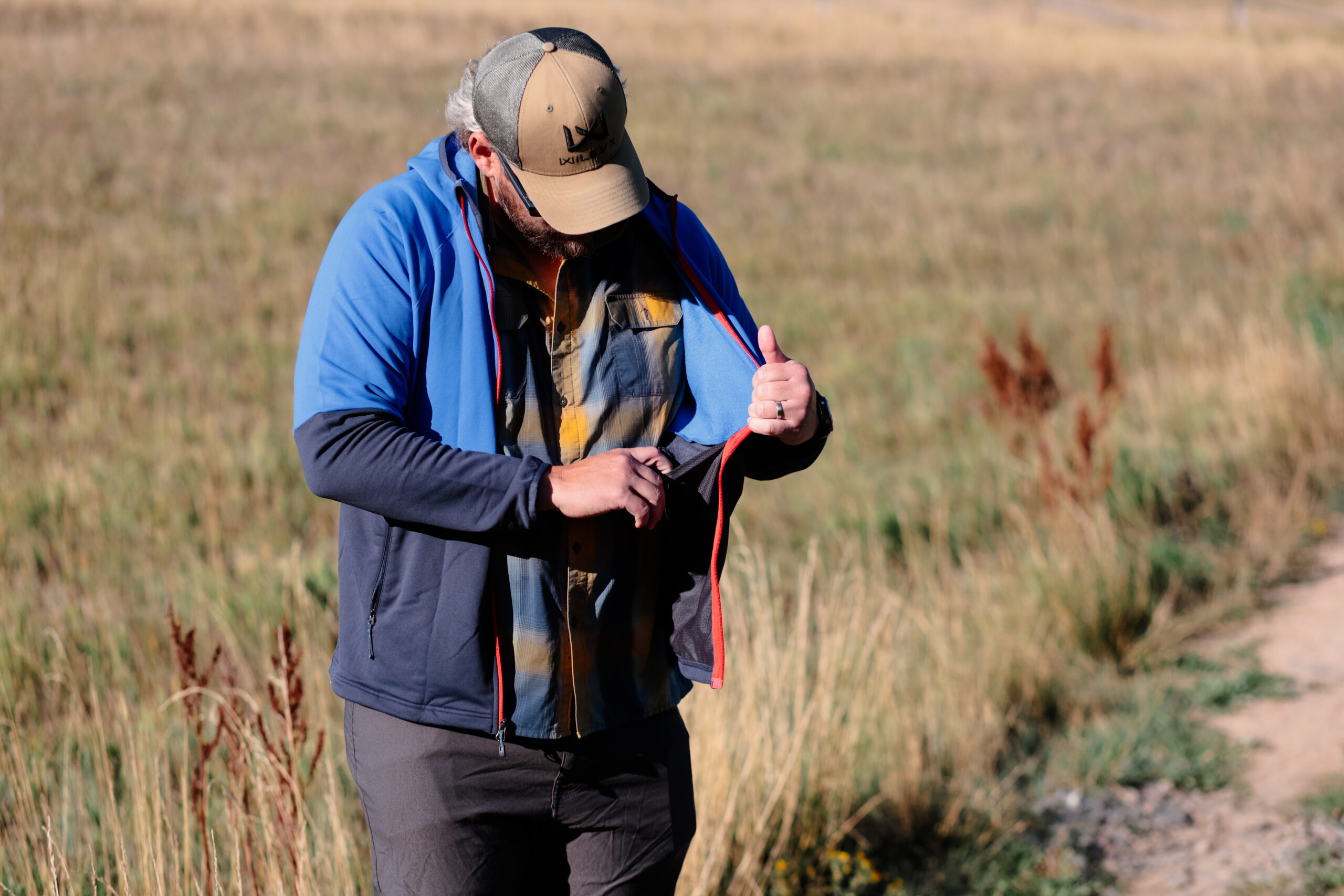 A man opens the drop pocket in a jacket.