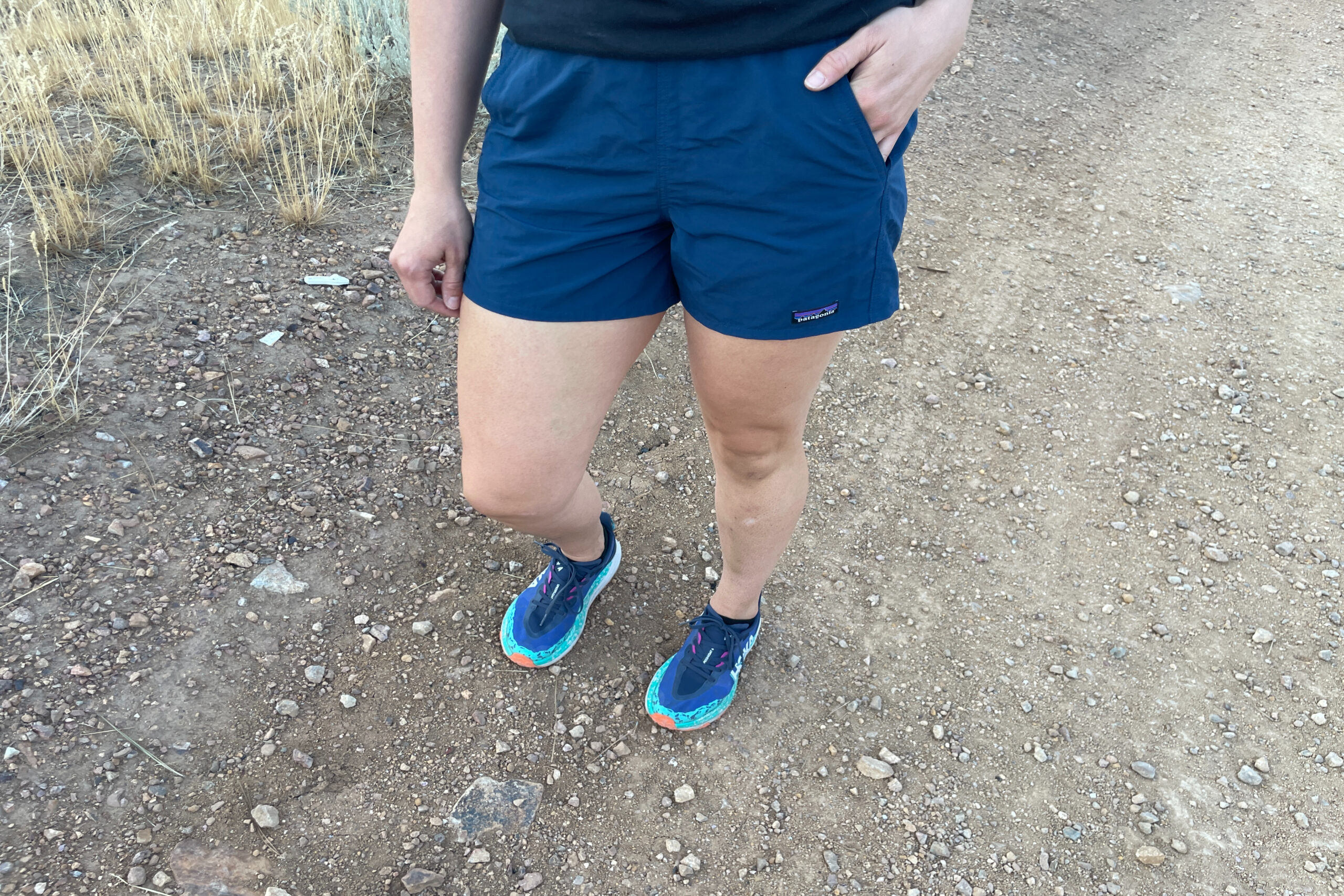 the lower half of a women walking with her hand in the pocket of her blue shorts from patagonia