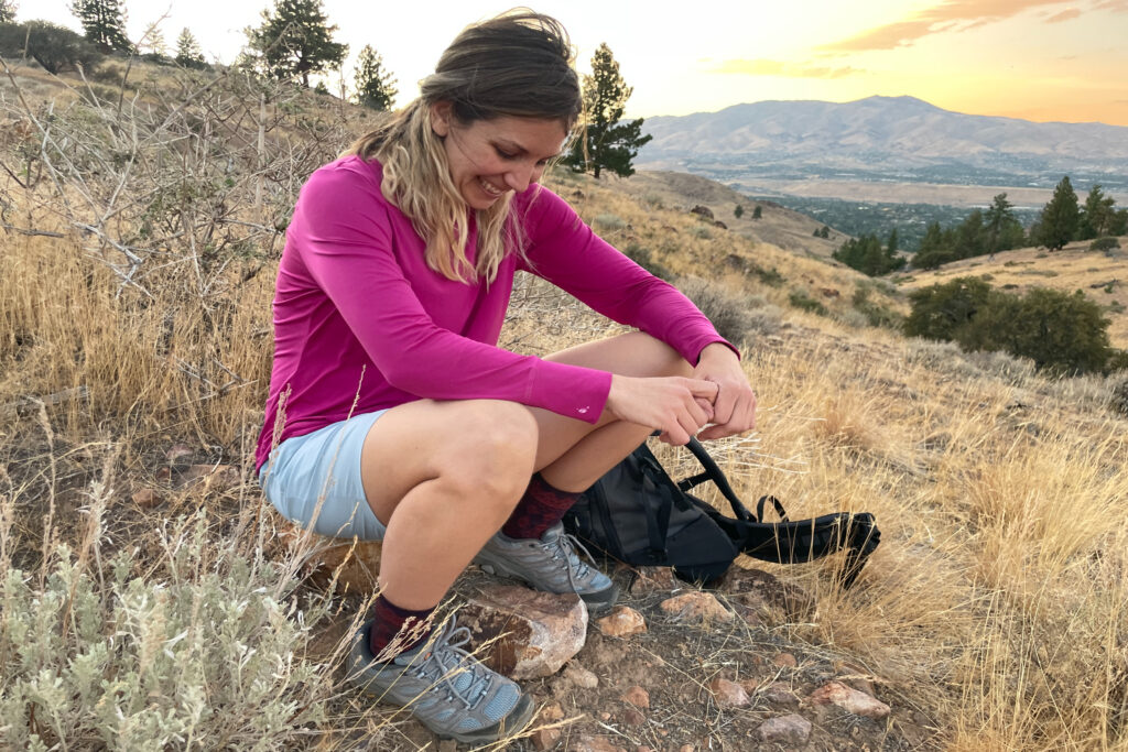 a hiker at sunset seated on a rocky butte wearing merrell moab hiking shoes