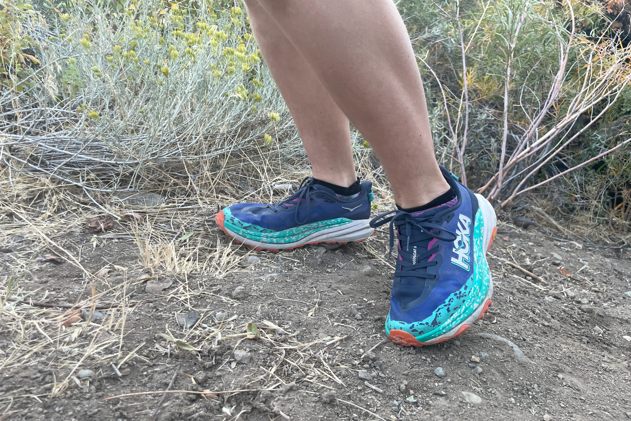 the lower legs and feet of a hiker wearing the hoka speedgoat 6 hiking shoes