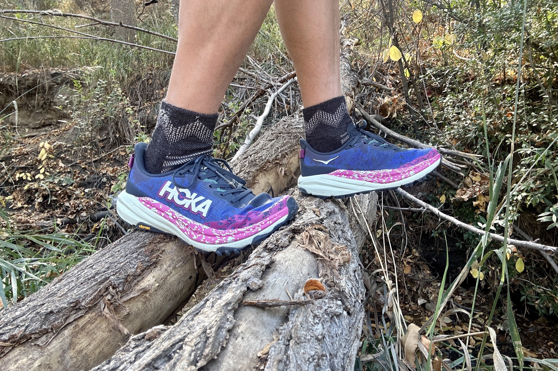 Close up of a person wearing shoes and balancing on a log.