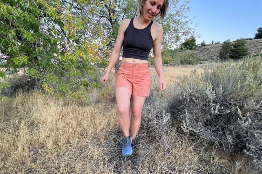 a women hiking in dry desert fields in orange patagonia shorts