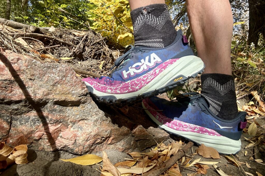 Close up of a person wearing shoes climbing up some rocks.