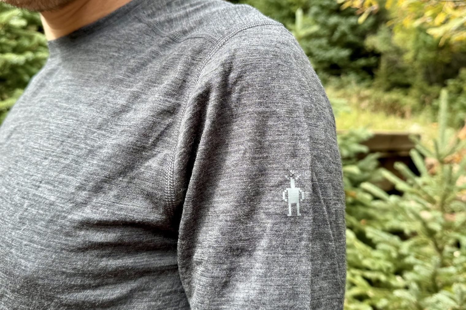 A close up of the shoulder logo on the Smartwool Classic All-Season base layer. Trees are in the background.