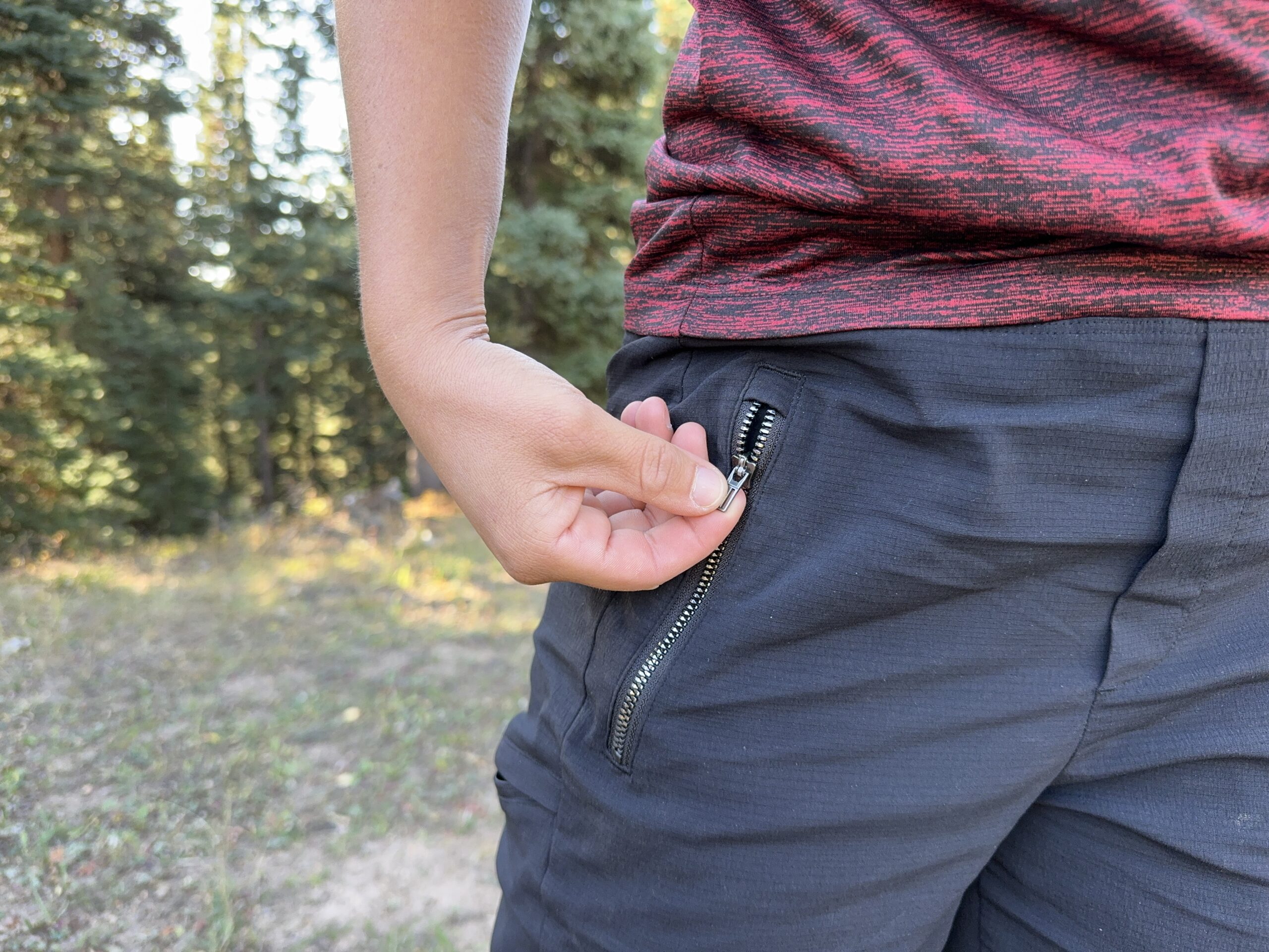 Close up of a zipper on the Athleta pants with a hand pulling it open.