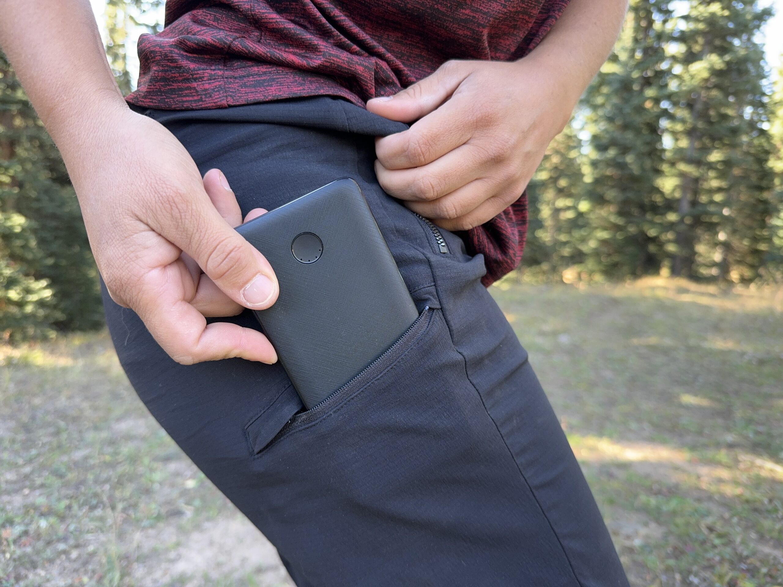 A person's hand placing a power bank into the leg pocket of the Athleta Trekkie pants.