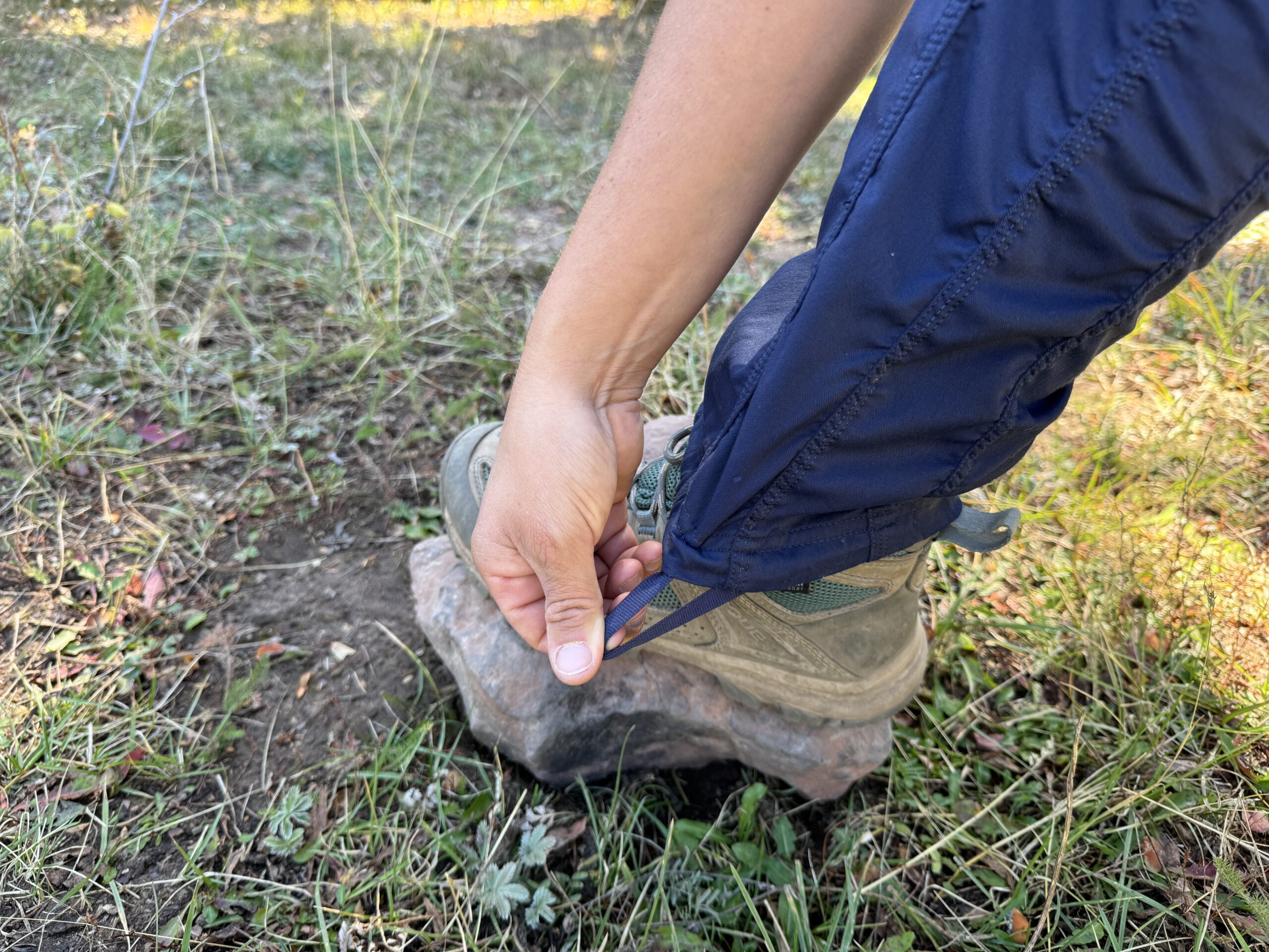 a hiker cinching the ankle drawcord on the aphrodite 2.0 pants