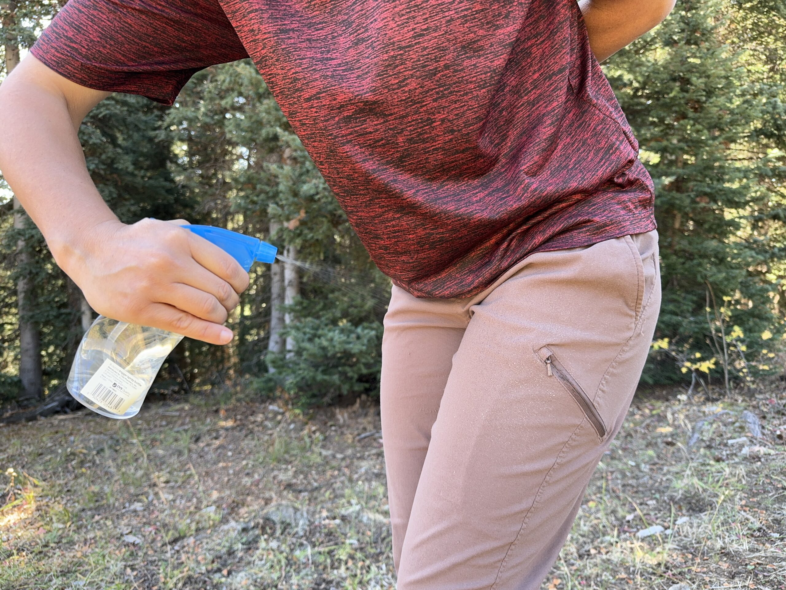 A person sprays the Mountain Hardwear Dynama pants with a squirt bottle while the same person is wearing them.