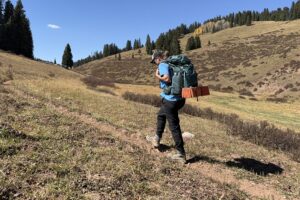 A backpacker wearing the Athleta Trekkie pants walks on a trail in the mountains.