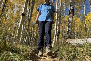 a day hiker wearing the north face aphrodite 2.0 pants on a trail through an aspen forest