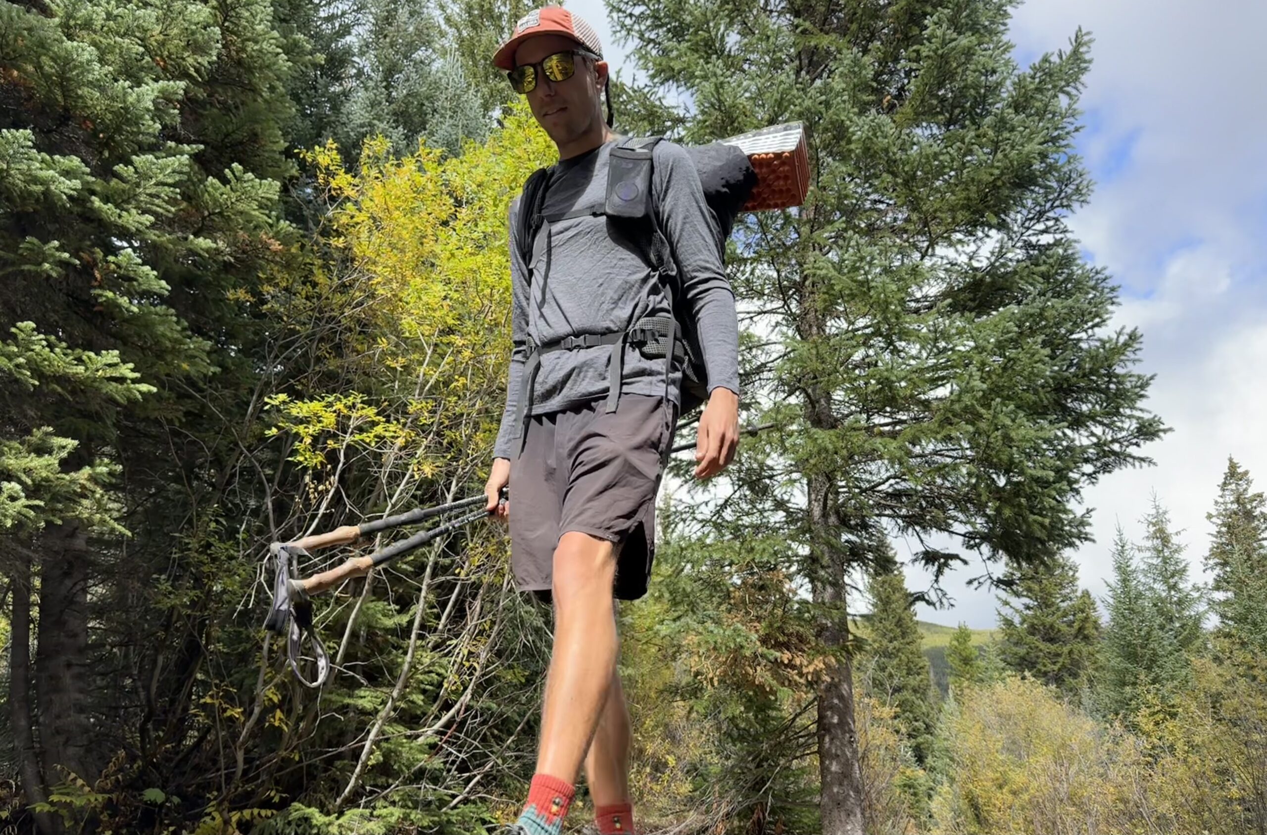 A hiker walks through the woods wearing the Smartwool Classic All-Season base layer. Trees are in the background.