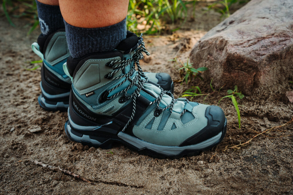 Hiker standing on a sandy patch wearing Salomon Quest 4 GTX Women's Hiking Boots