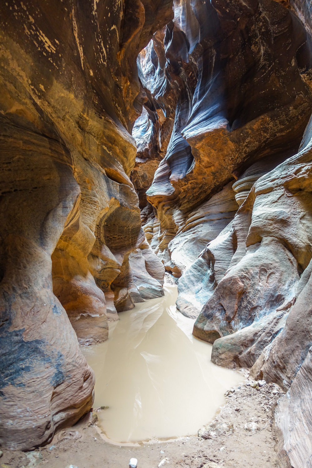 a brown pool of water in the paria slot canyon