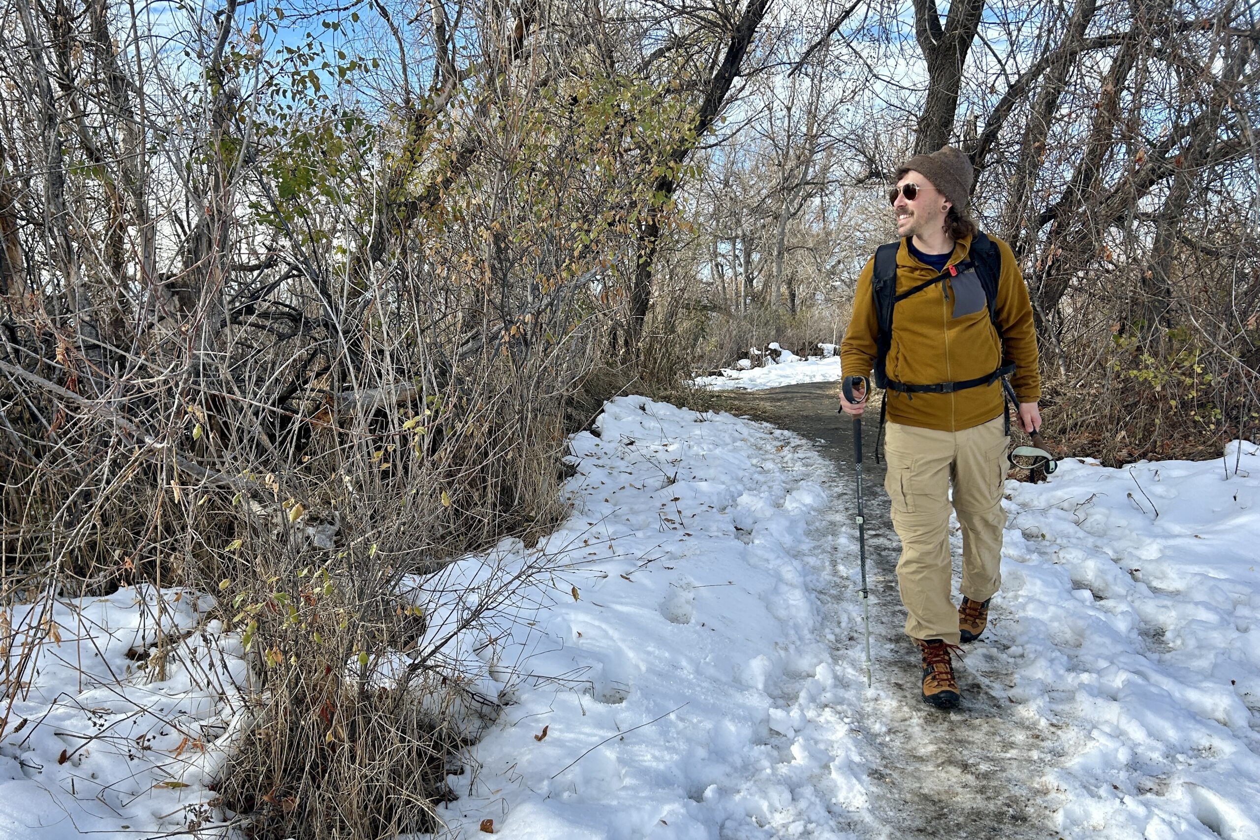 A man hikes through a snowy wilderness area on a bluebird day.