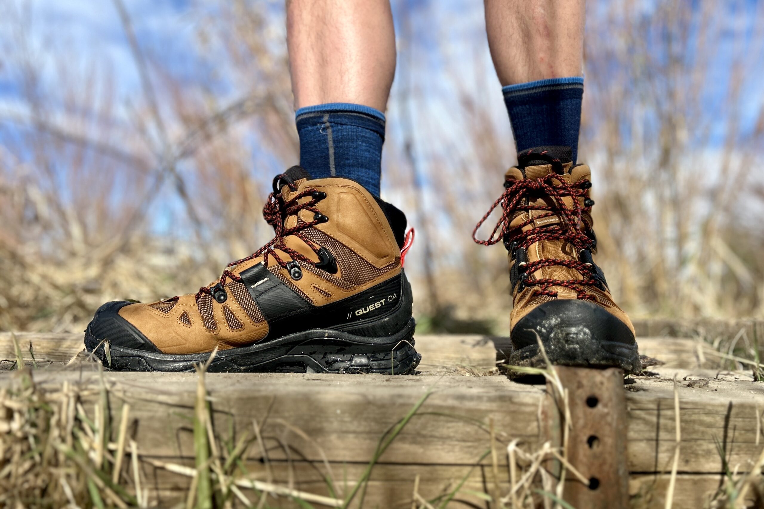 Close-up image from the knees down of a person walking in hiking boots in a wilderness area.