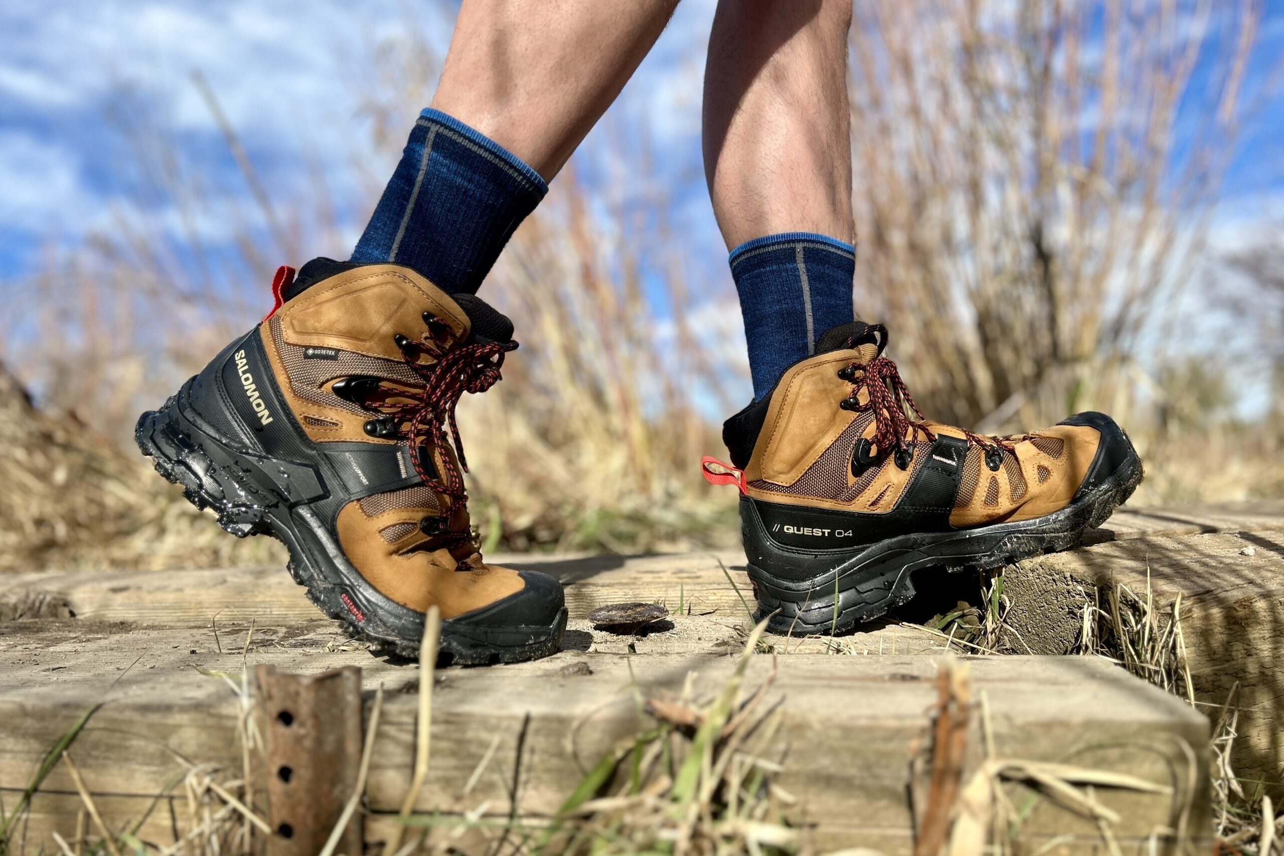 Close-up image from the knees down of a person walking in hiking boots in a wilderness area.