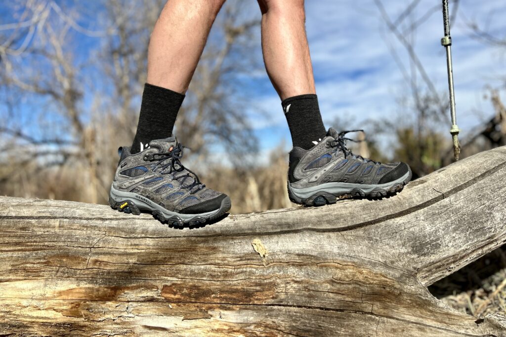 Close-up image from the knees down of a person walking in hiking boots in a wilderness area.