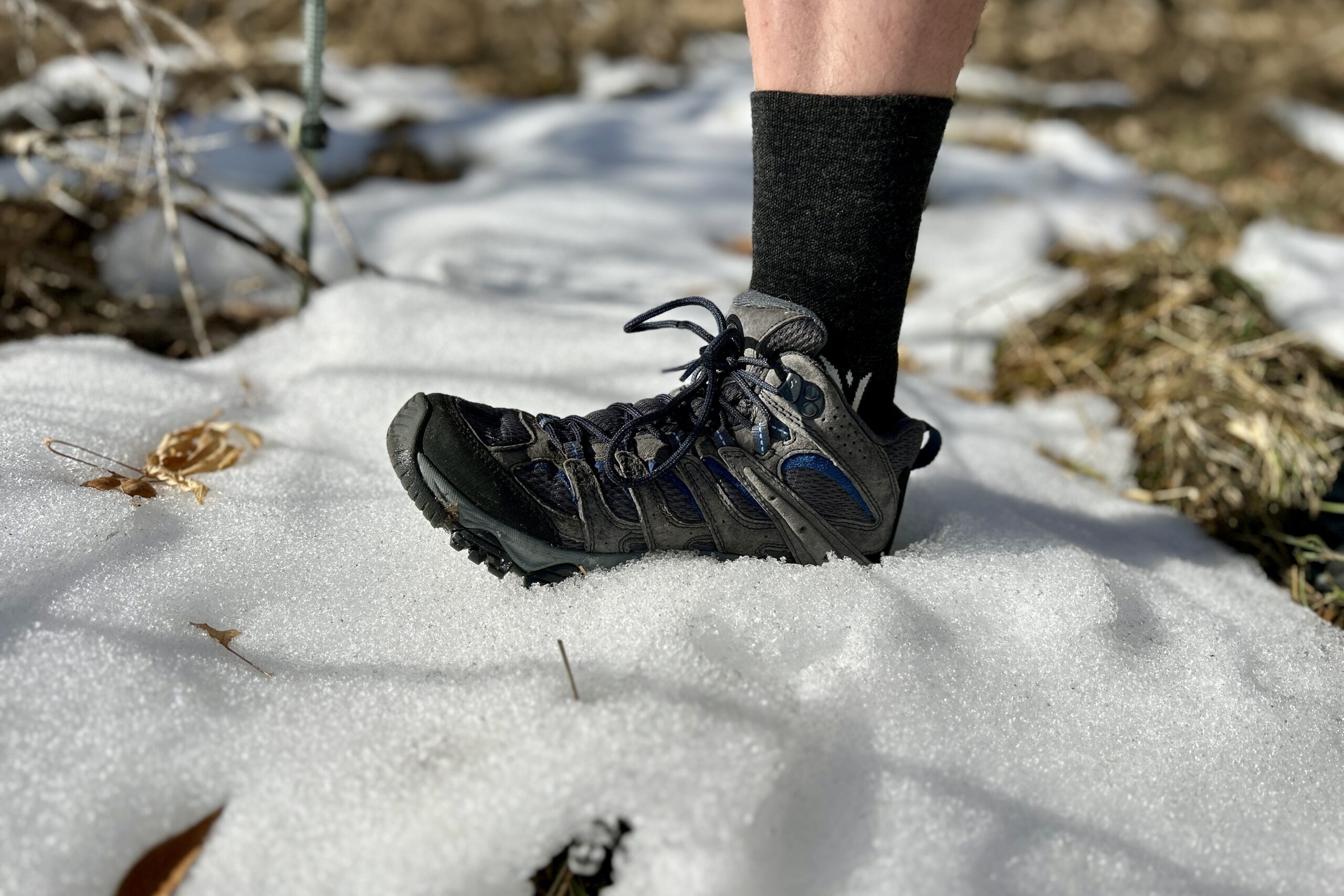 Close up image of a person stepping into snow with their hiking boot.