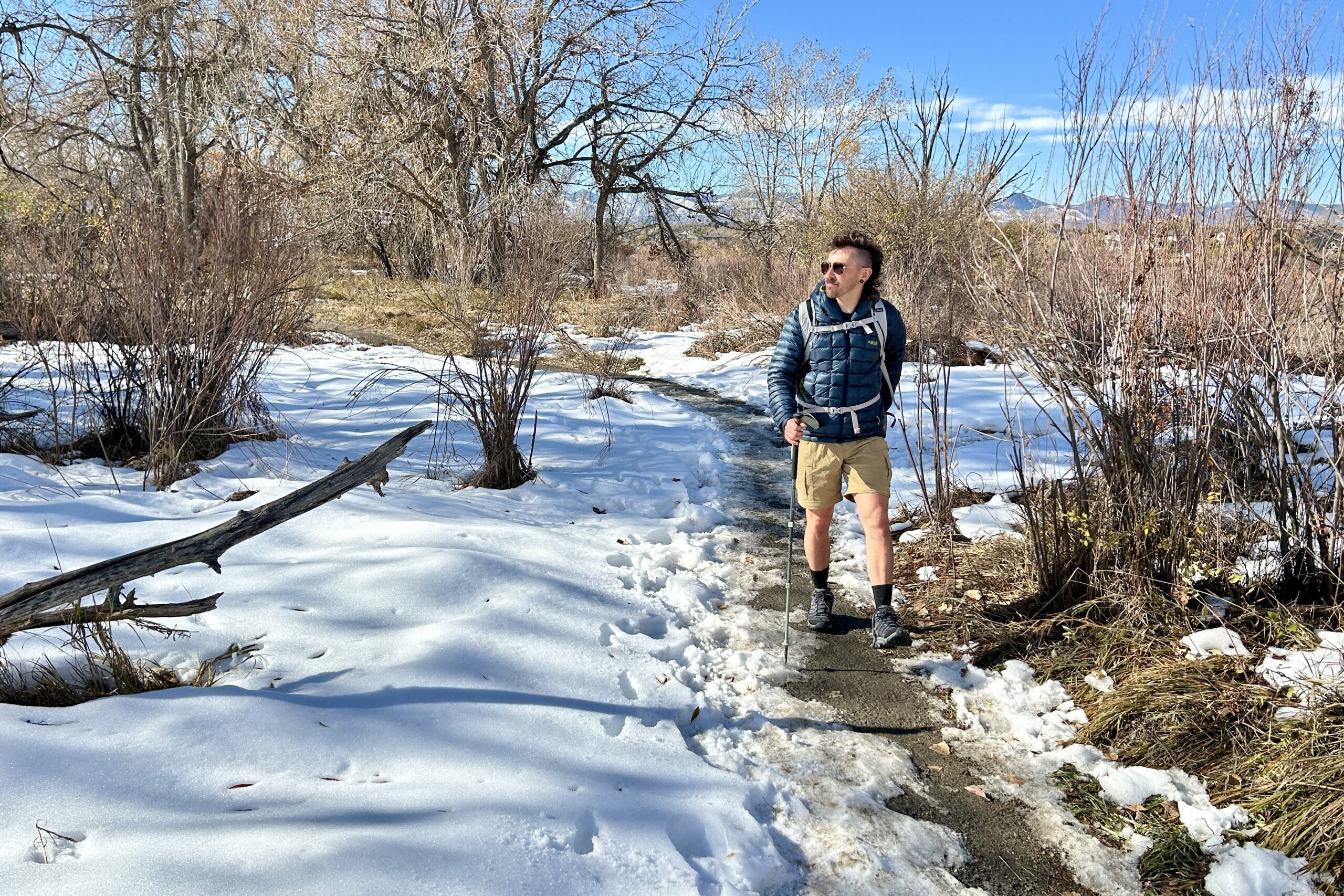 A man hikes through a snowy wilderness area on a bluebird day.