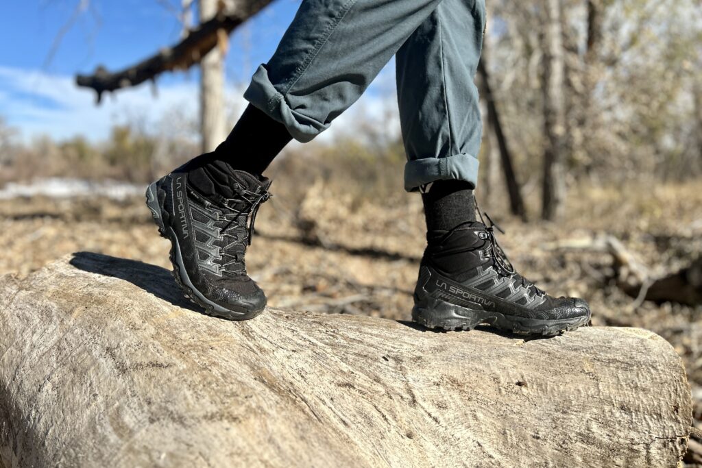 Close-up image from the knees down of a person walking in hiking boots in a wilderness area.