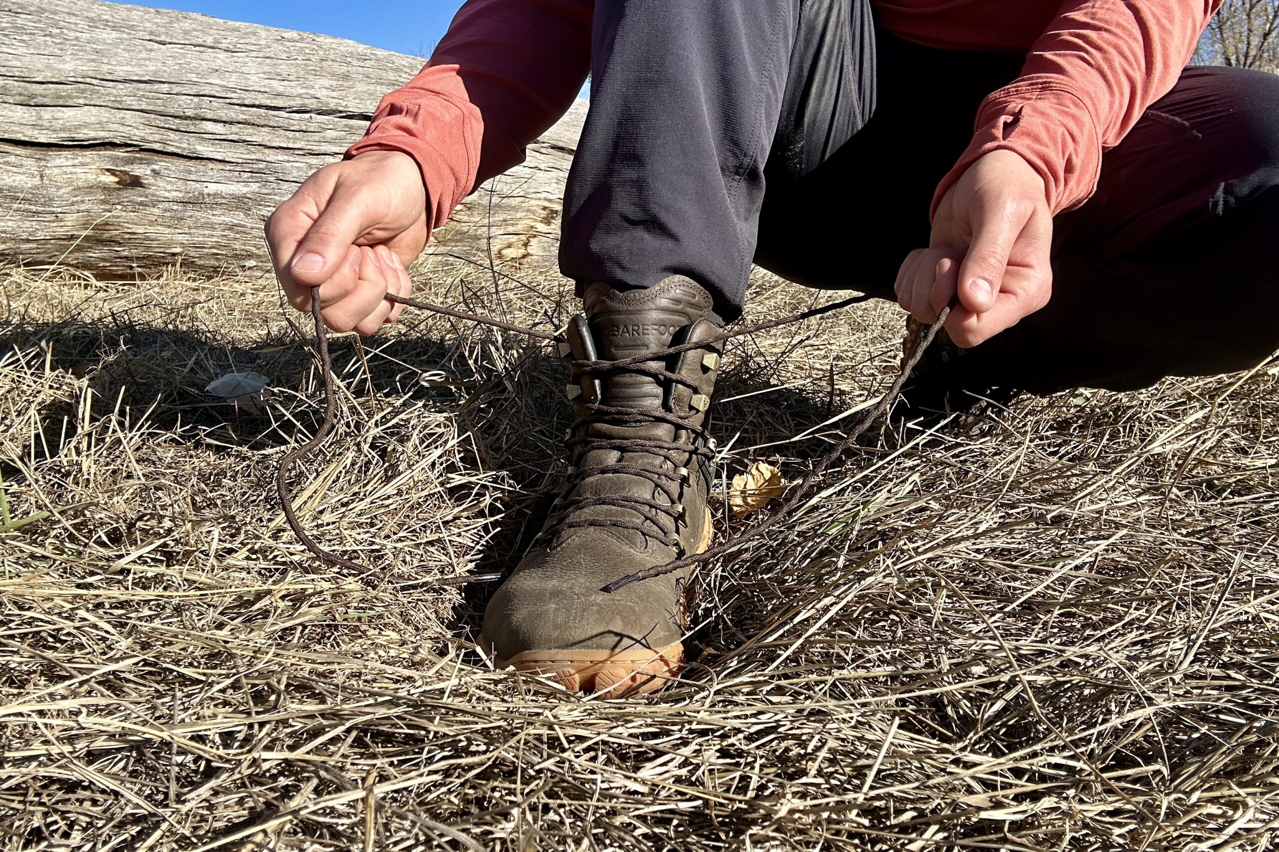 Close up image from knees down of a person tying a pair of boots.