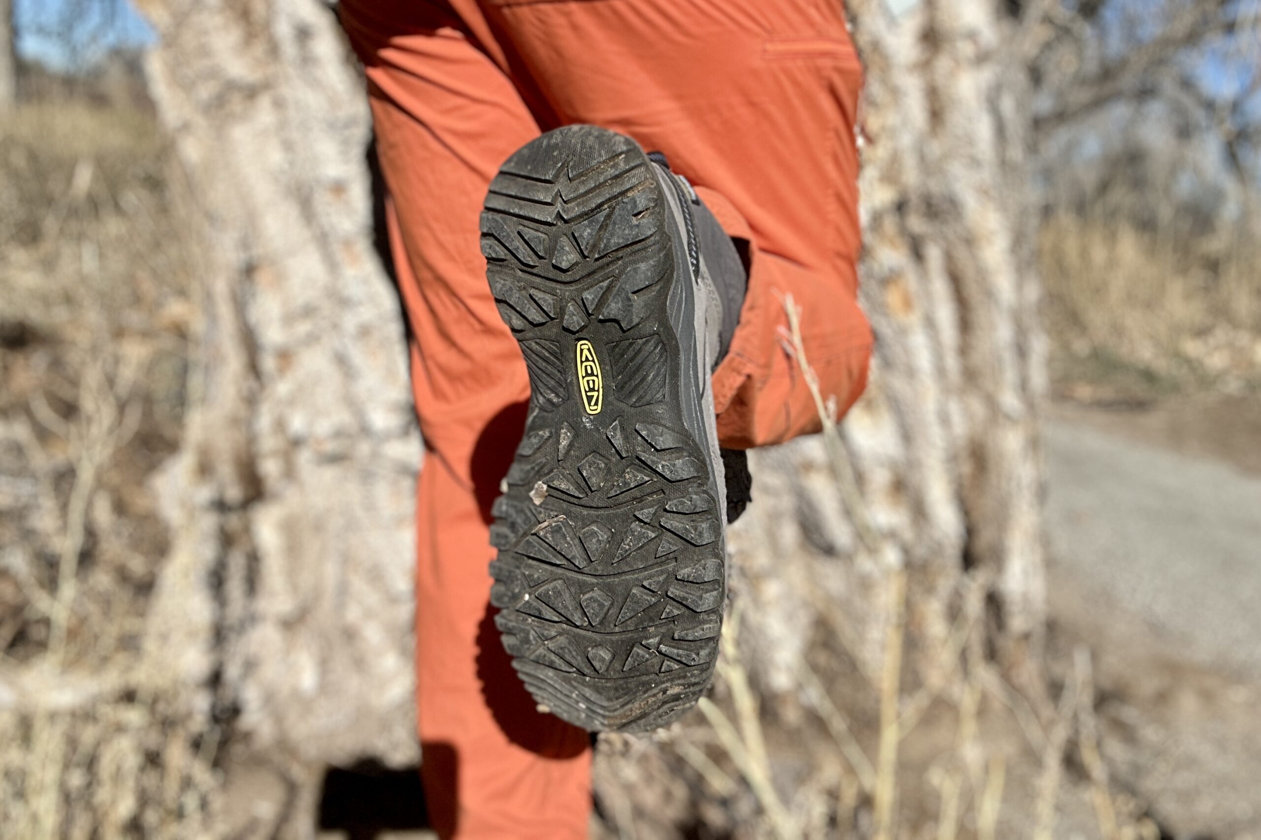 Close up image of a person showing the tread on the bottom of their boots.