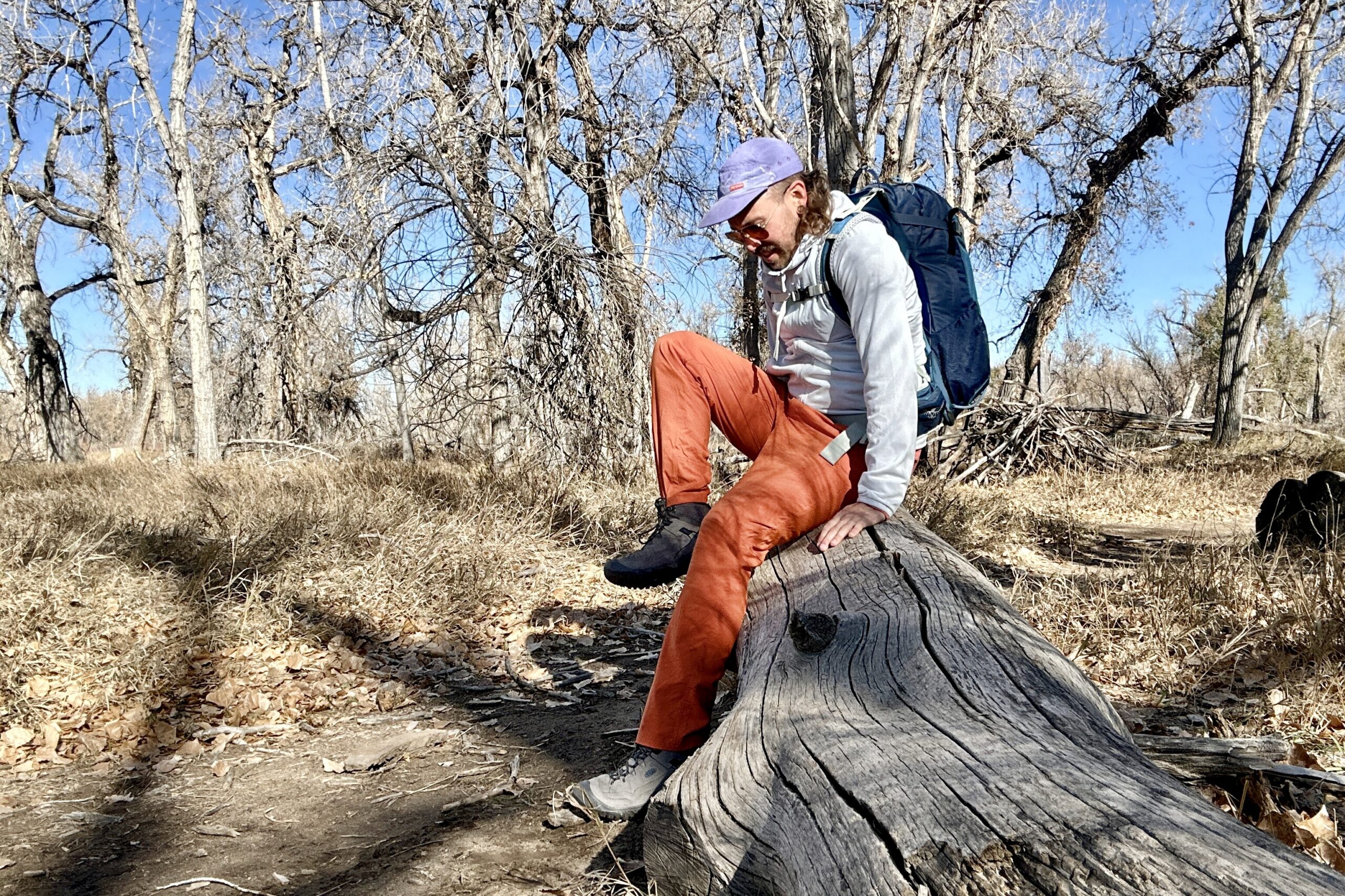 A hiker sits a log in a wilderness area.