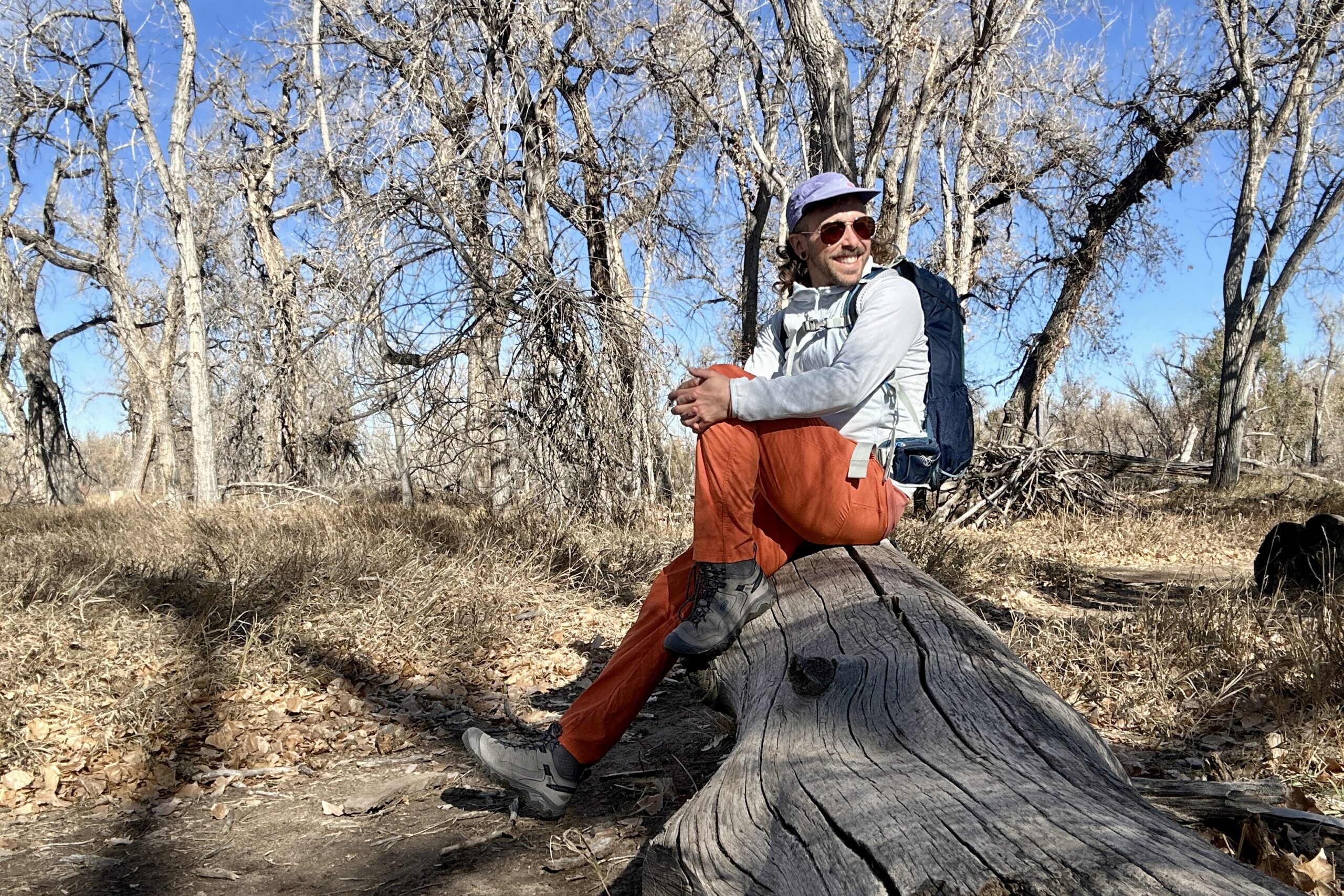 A hiker sits a log in a wilderness area.