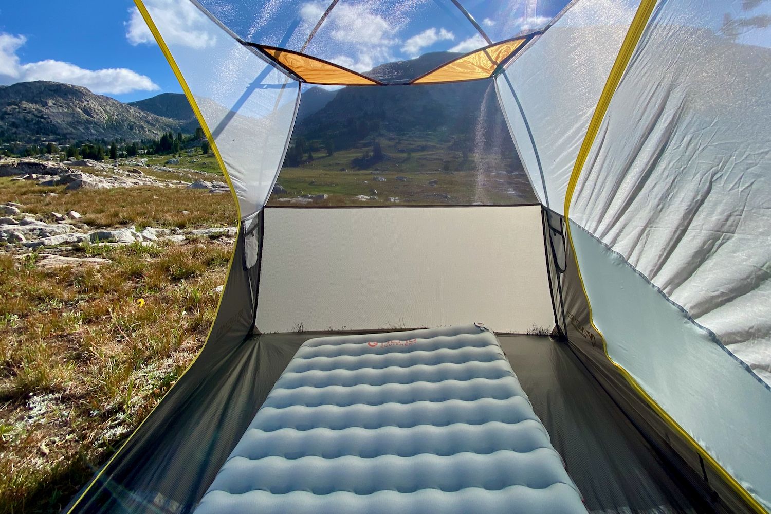 The Nemo Tensor sleeping pad inside a tent with the door open and beautiful mountains in the background