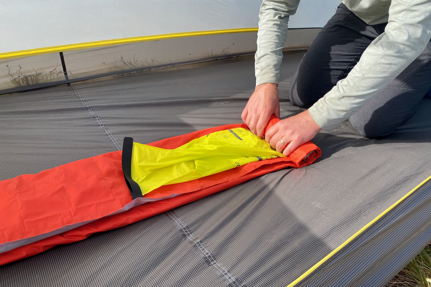 a backpacker rolls up their sleeping pad and vortex inflating sack inside an empty tent