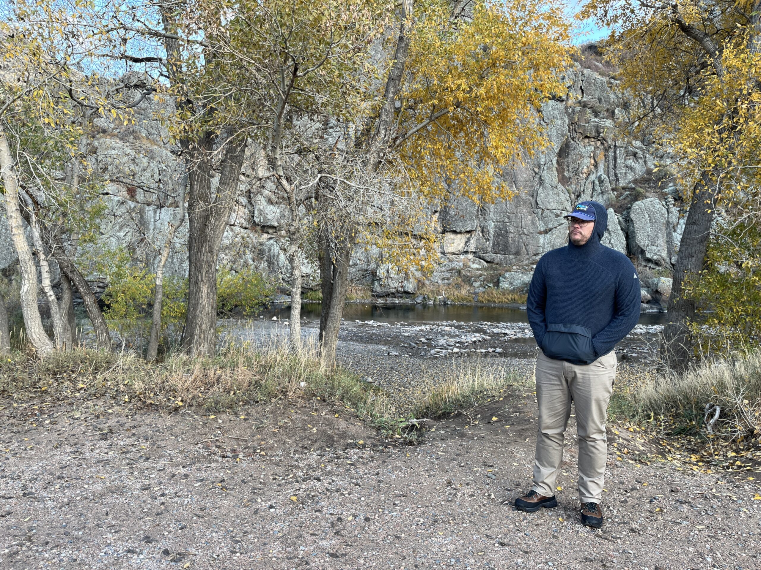 a man wearing an eddie bauer super sevens fleece in the fall foliage under aspen trees next to a river