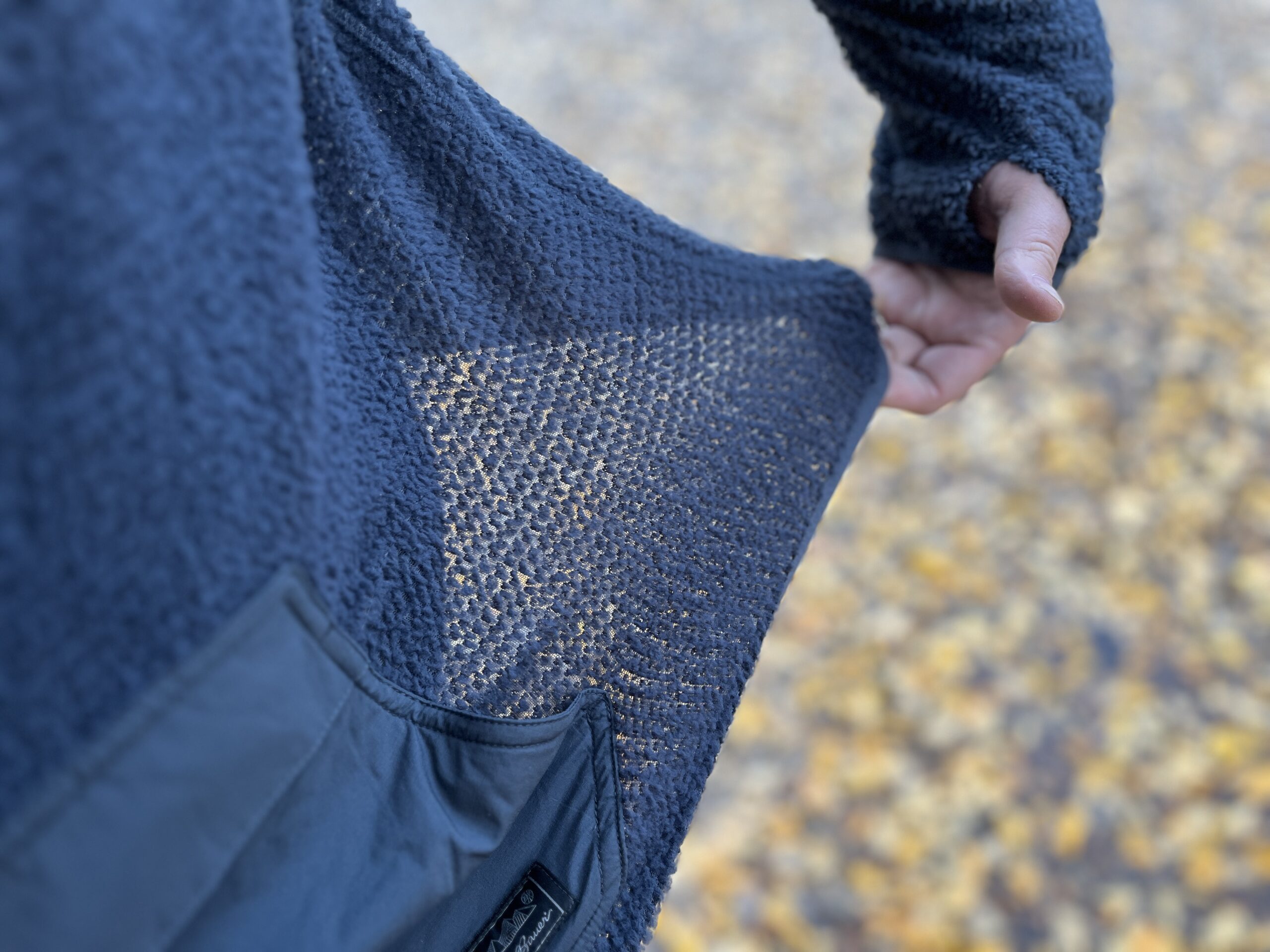 a man stretches out the fleece material of the eddie bauer super sevens to show how light the fabric is