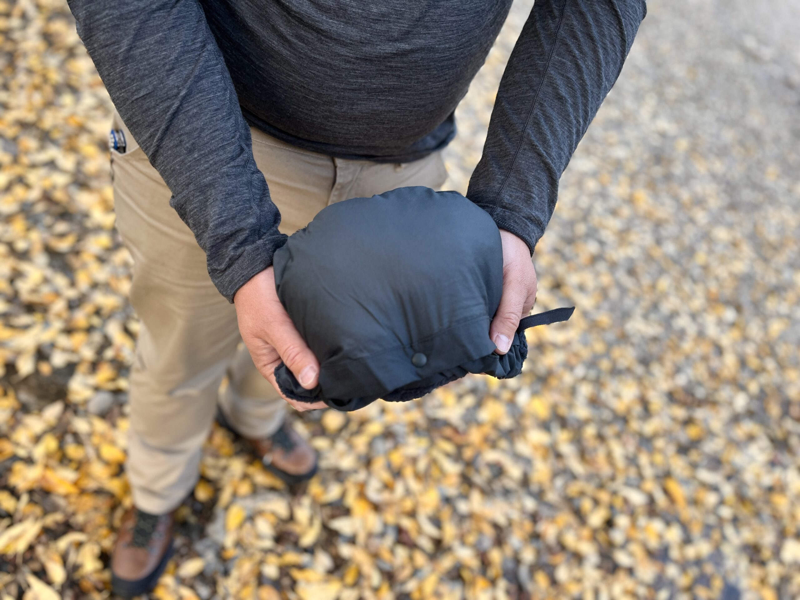 a man packs the eddie bauer super sevens fleece into its pocket pouch to show how small and packable it is.