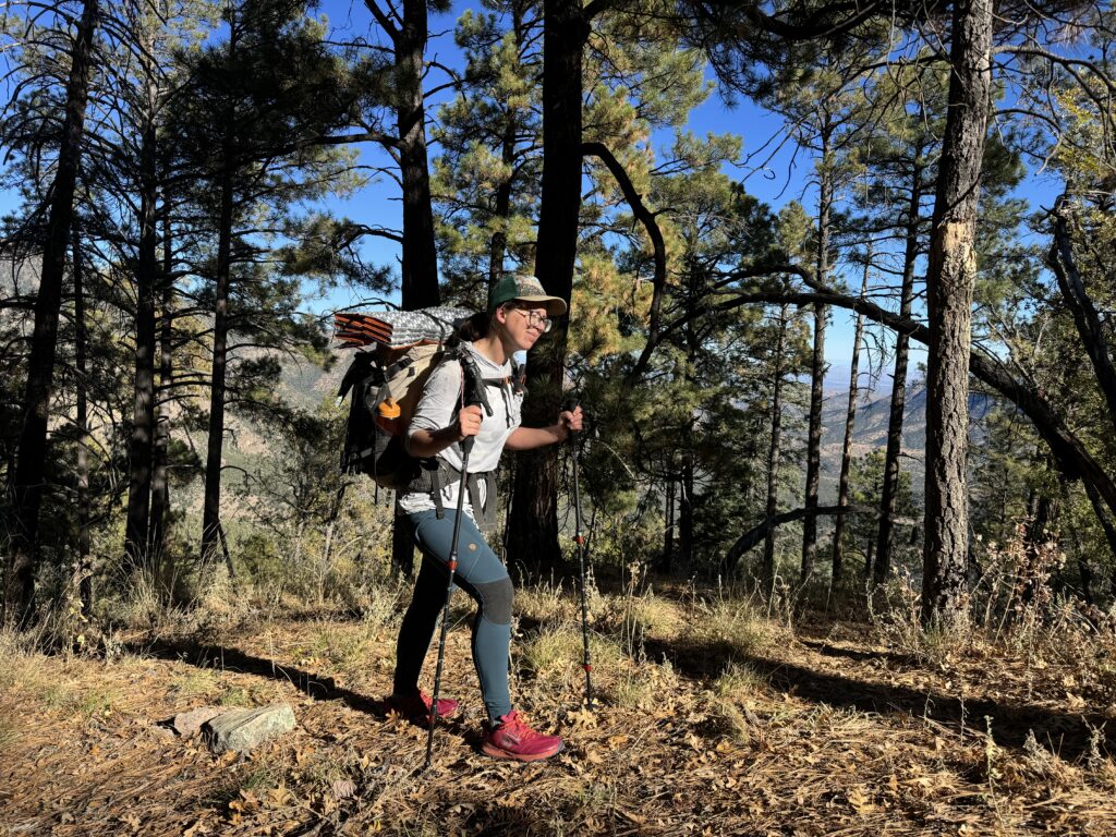 A person wearing the Abisko leggings and a backpack is walking down a trail in the woods.