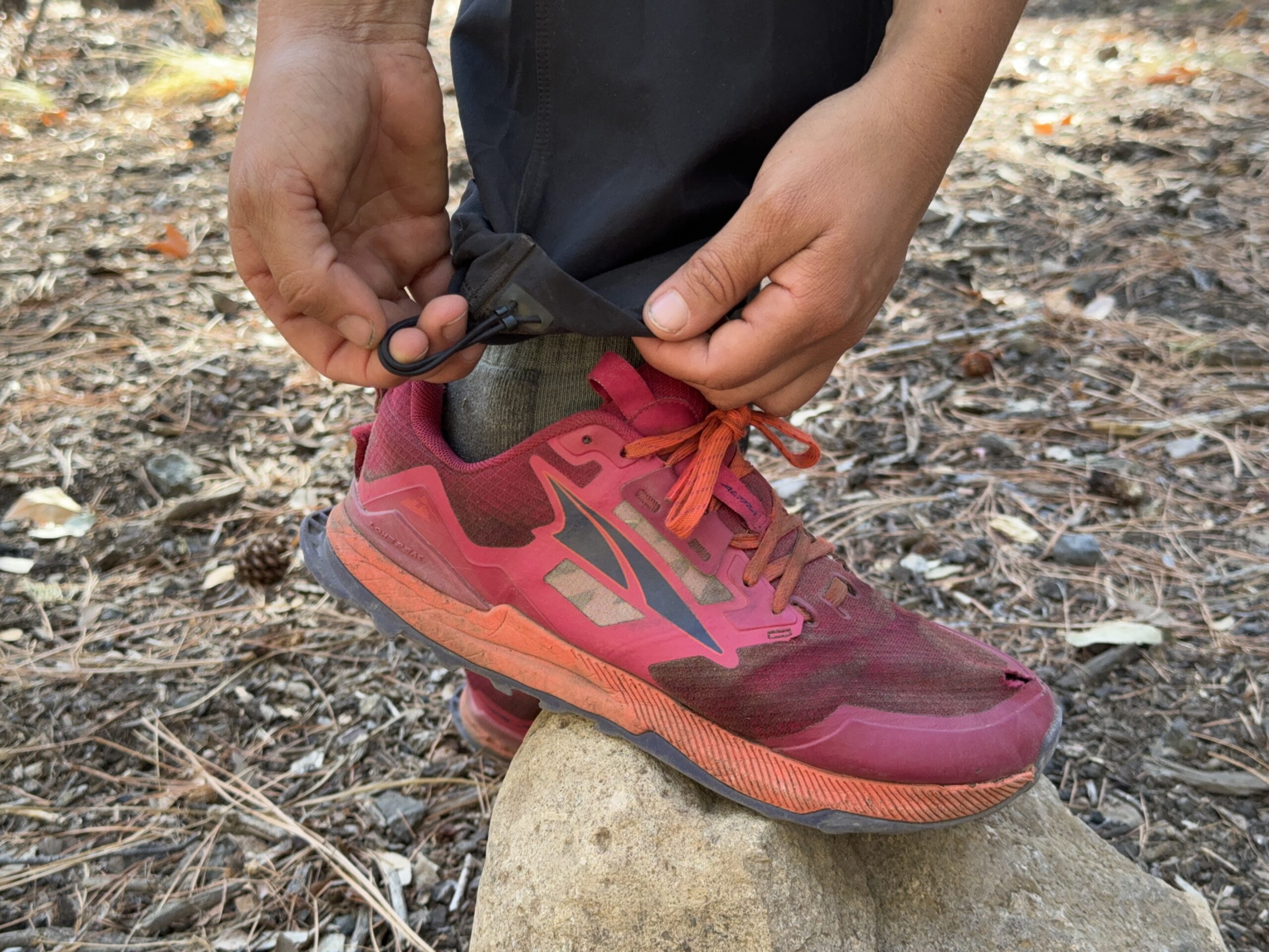 A close up of a hand demonstrating how the ankle cinch works on the Gamma pants.