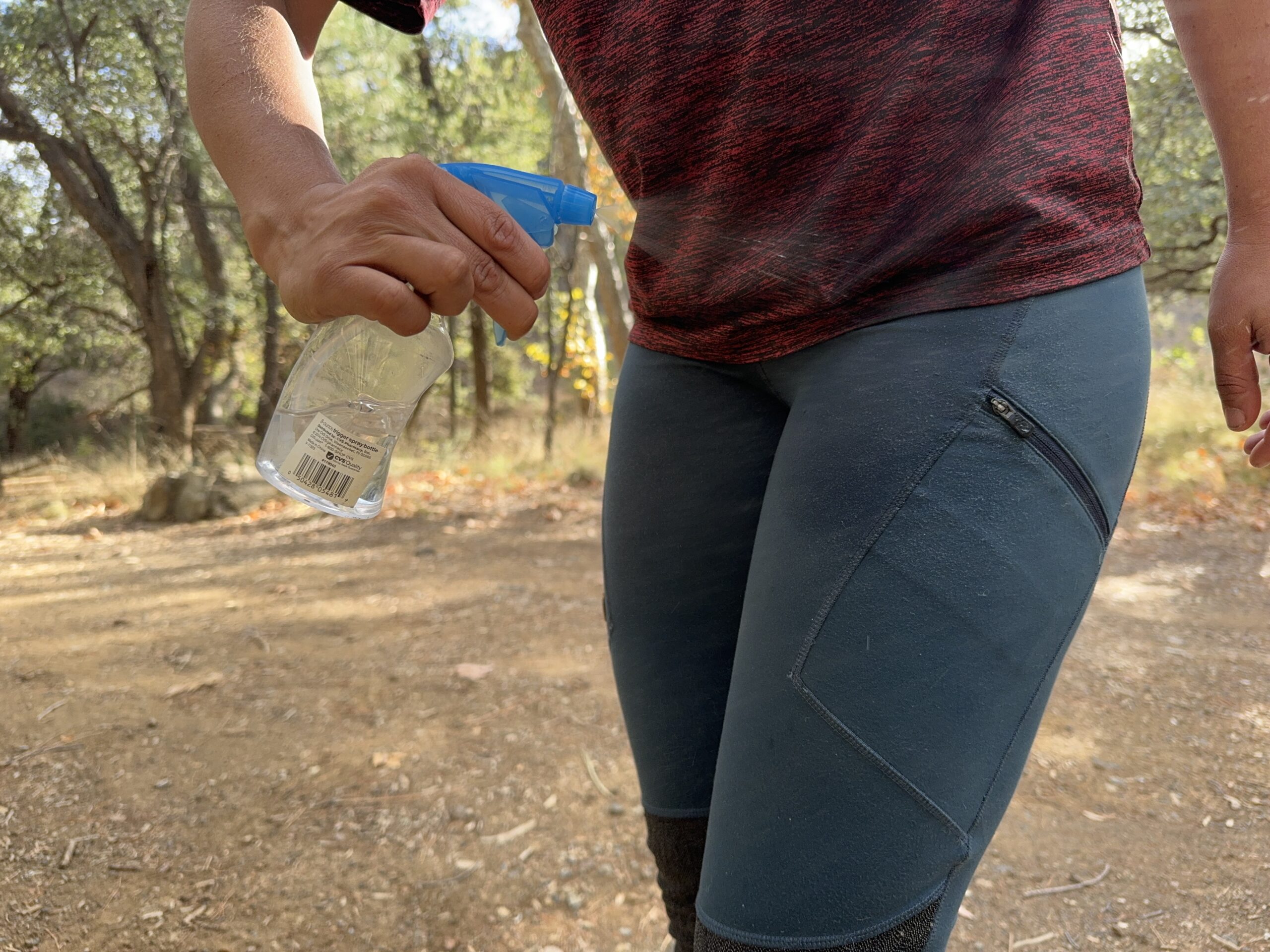 A hand is spraying the Fjallraven Abisko pants with water from a squirt bottle.