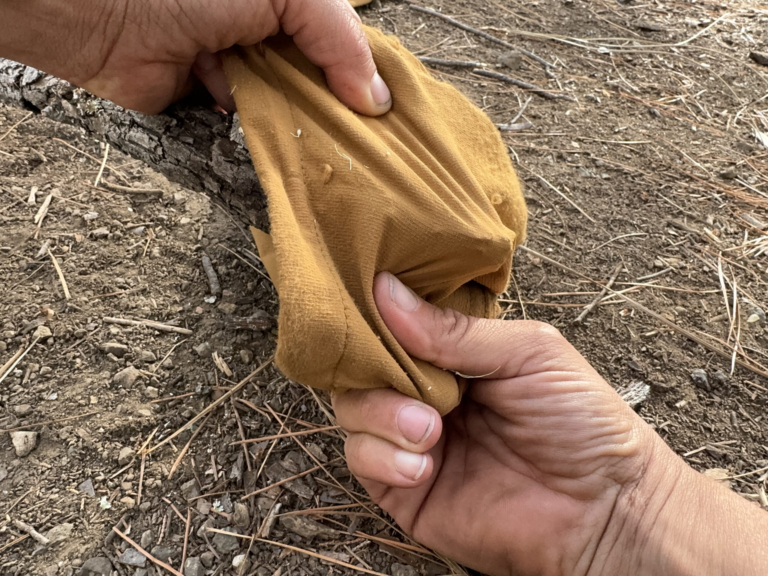 Close up of two hands stretching the fabric of the Ferrosi pants over a sharp stick.