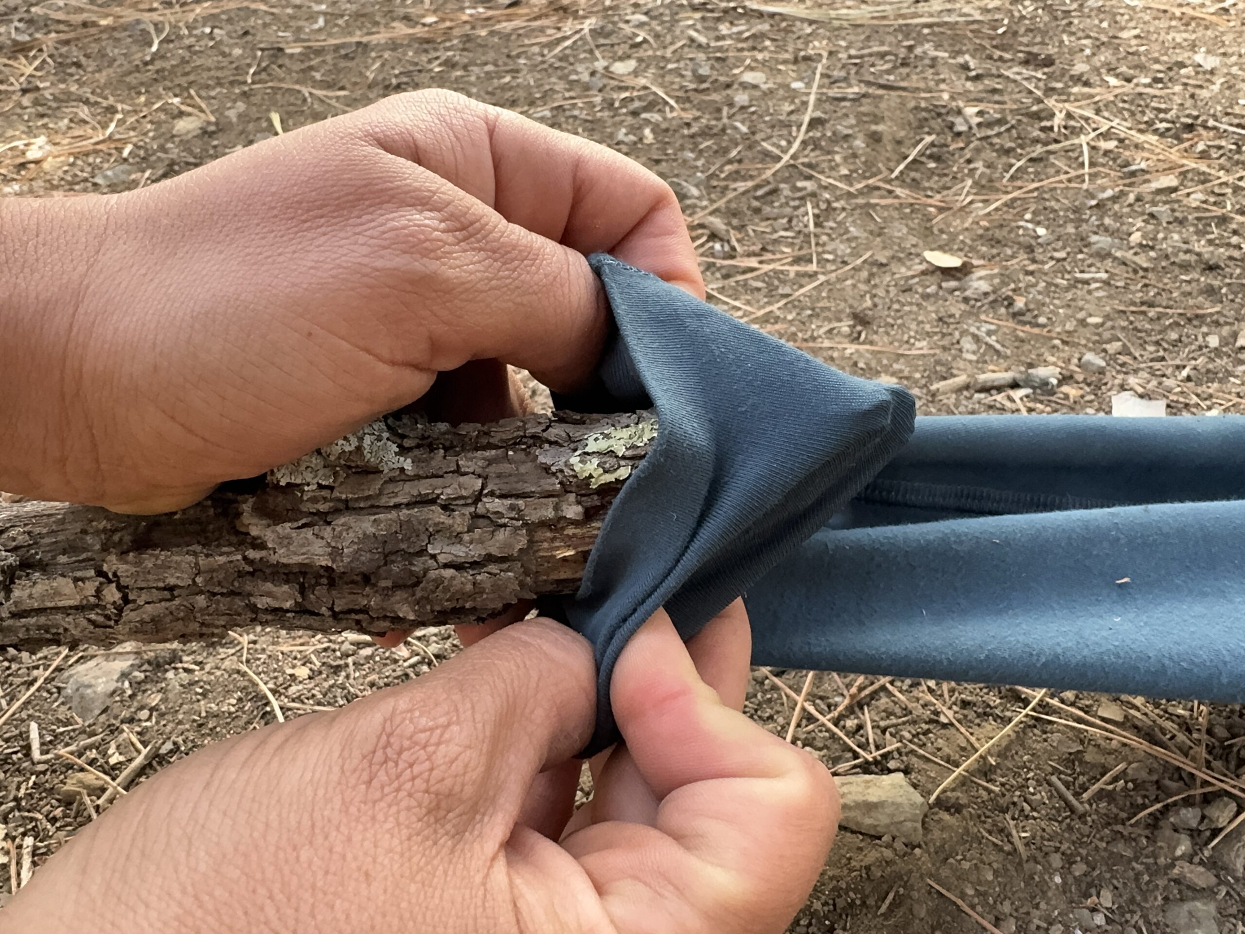 Close up of two hands stretching the fabric of the Abisko pants over a sharp stick.