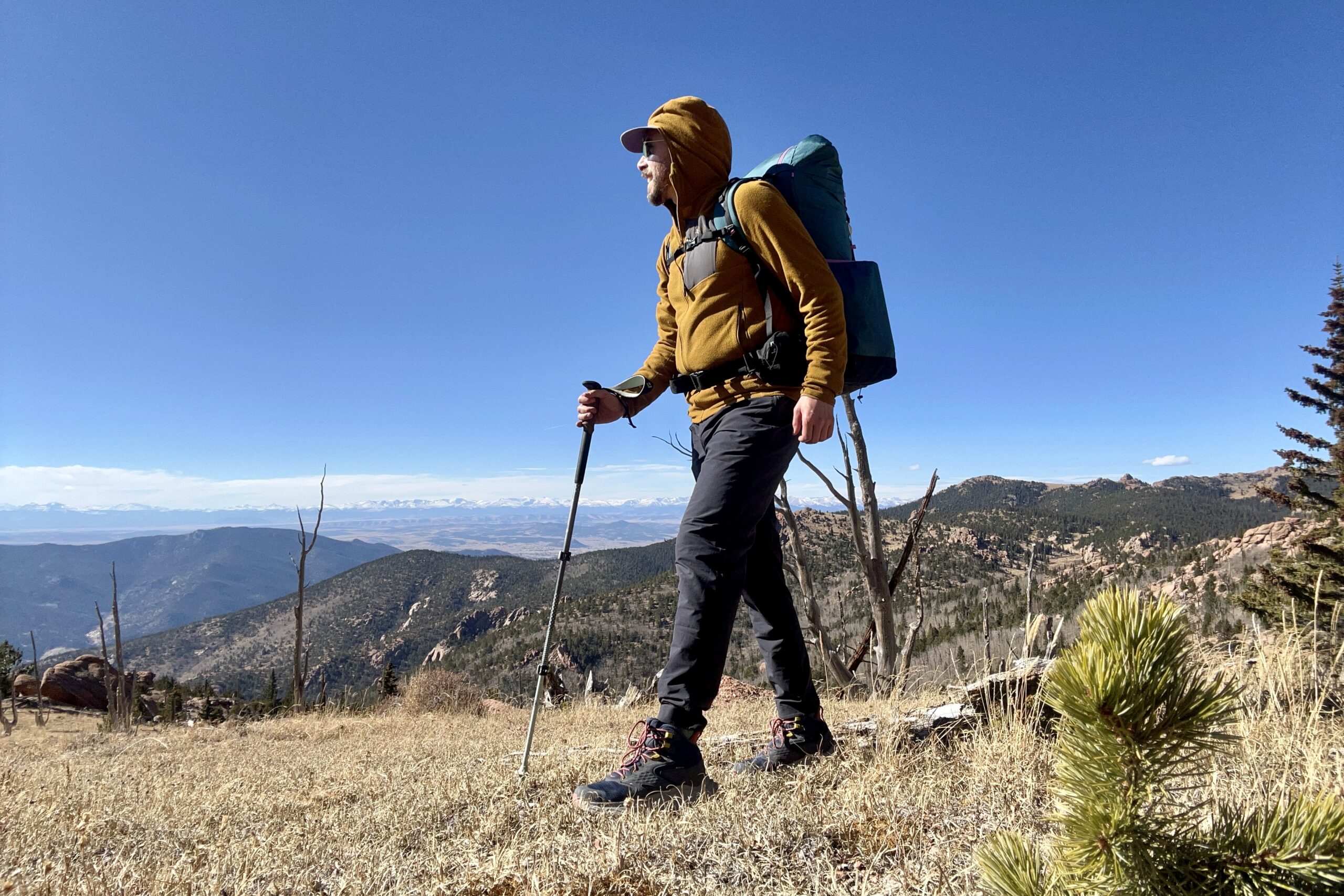 A man with a large backpacking backpack walks in a forest setting.