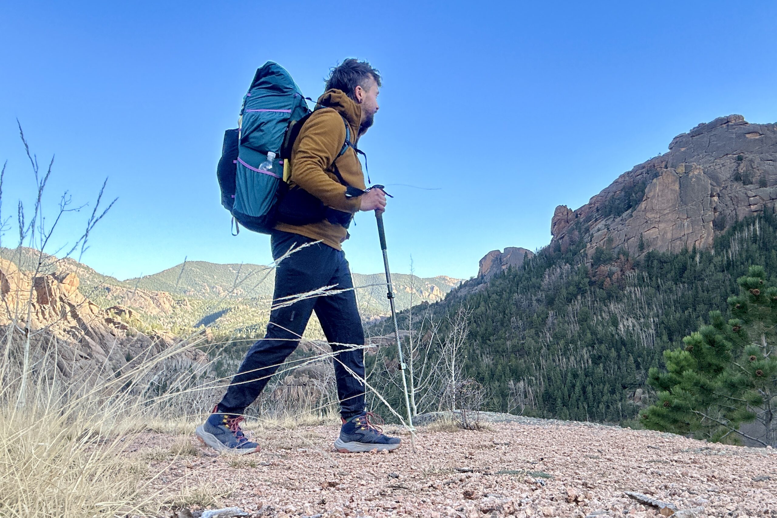 A man with a large backpacking backpack walks in a forest setting.