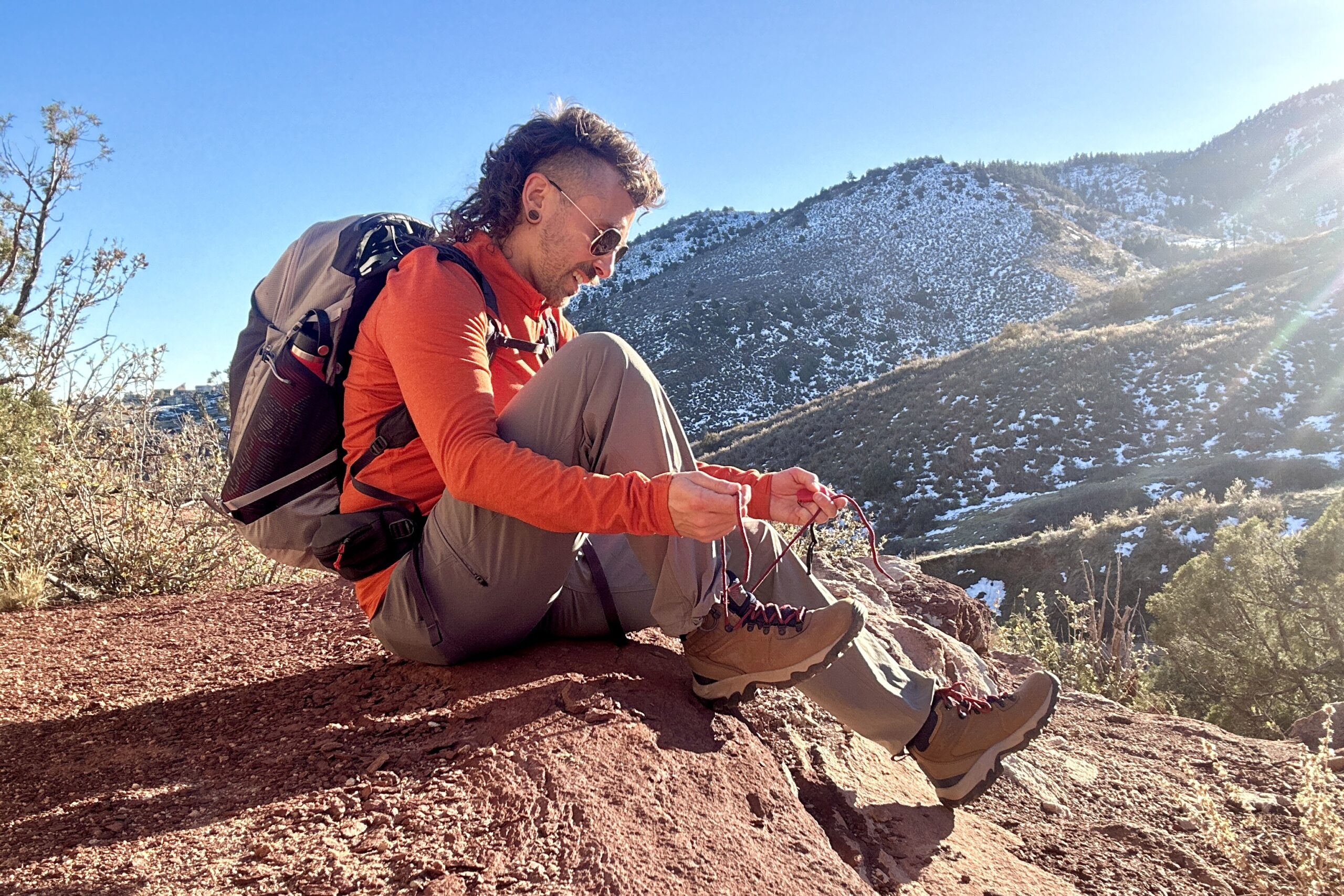 A man sits on a rock tying his boots.